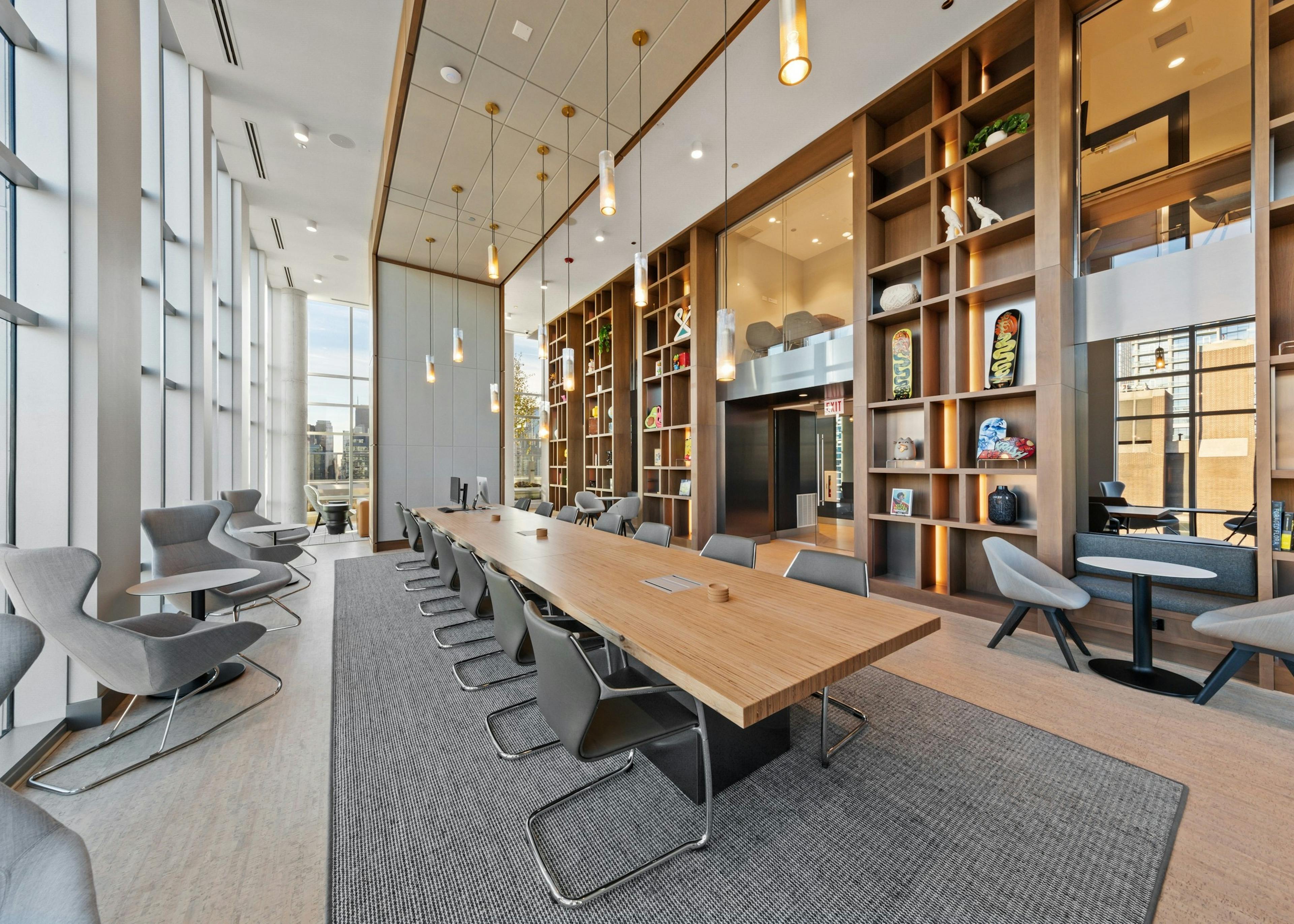 Luxurious collab space amenity at AMLI 808 featuring floor to ceiling windows and a modern table in front of sleek shelving
