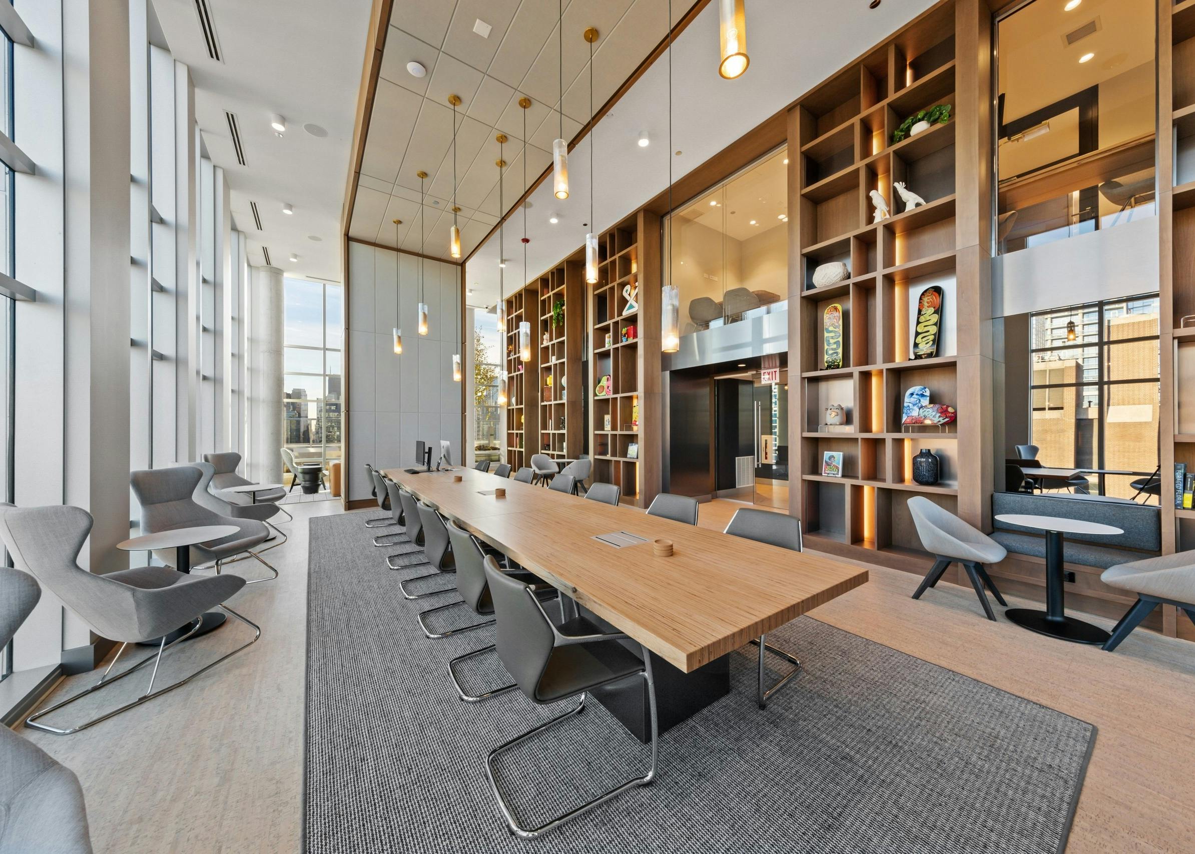 Luxurious collab space amenity at AMLI 808 featuring floor to ceiling windows and a modern table in front of sleek shelving