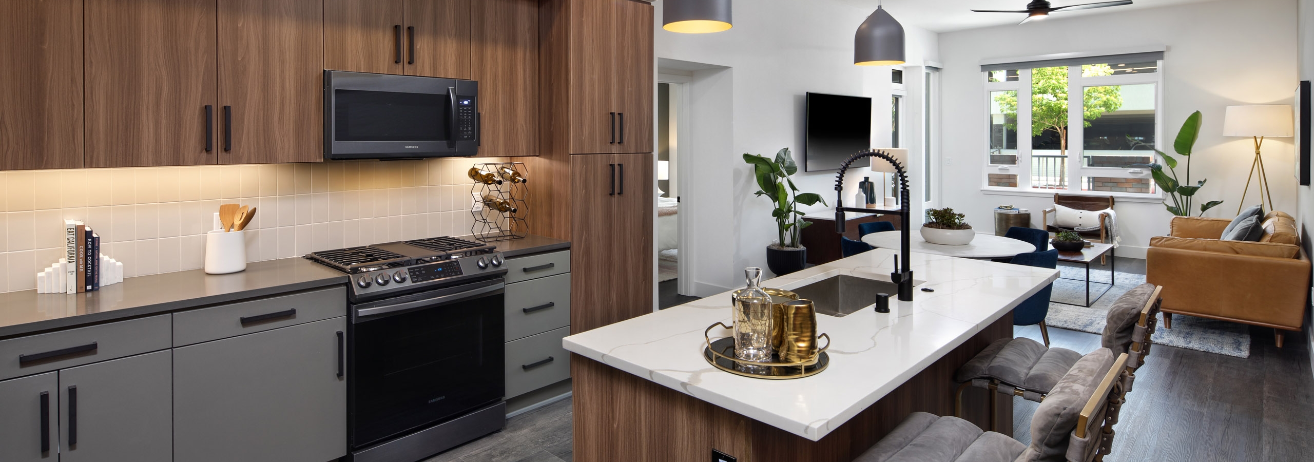 Dark wood kitchen with gas range and hardwood flooring facing dining table and living room at AMLI Old Pasadena apartments