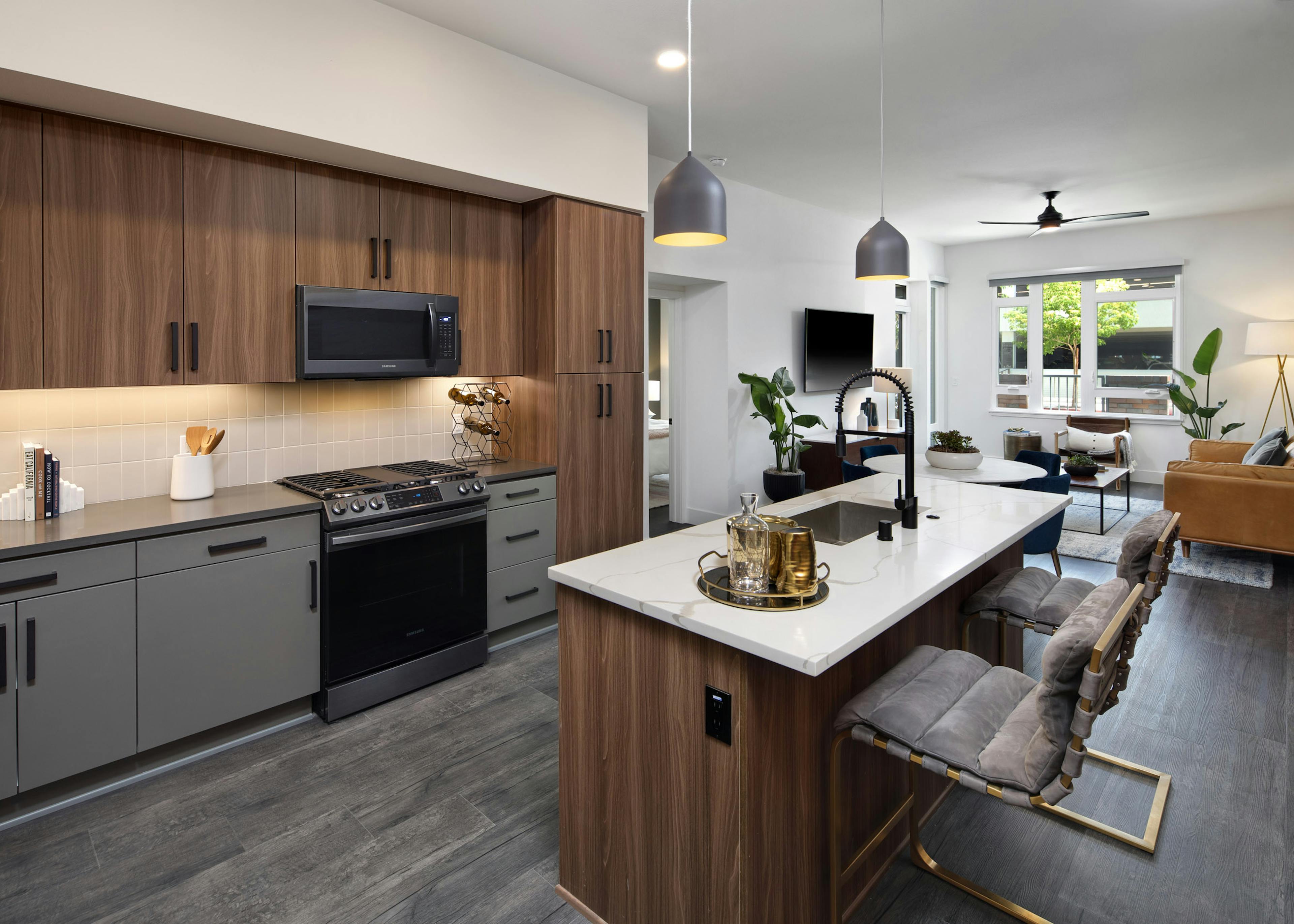 Dark wood kitchen with gas range and hardwood flooring facing dining table and living room at AMLI Old Pasadena apartments