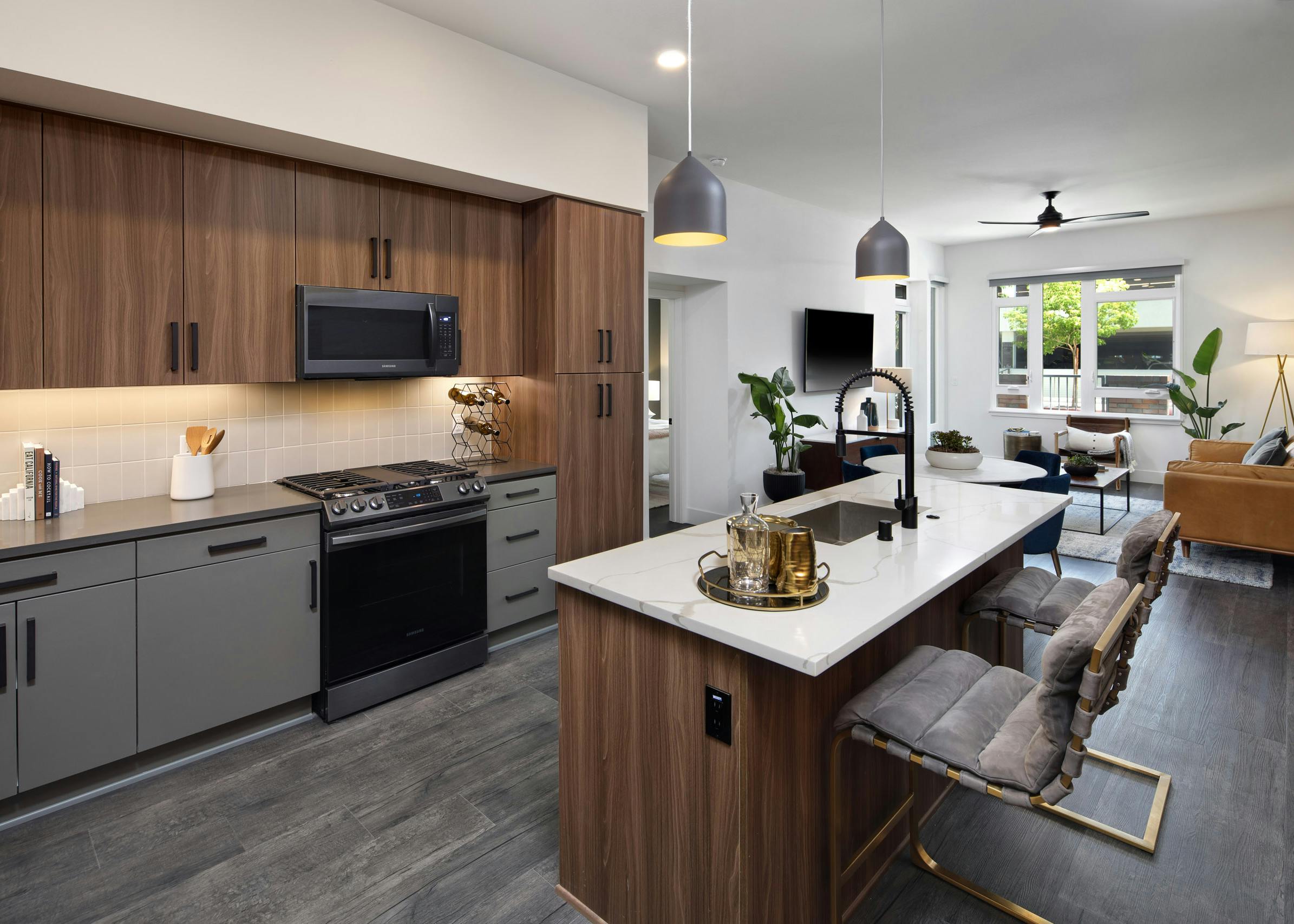 Dark wood kitchen with gas range and hardwood flooring facing dining table and living room at AMLI Old Pasadena apartments