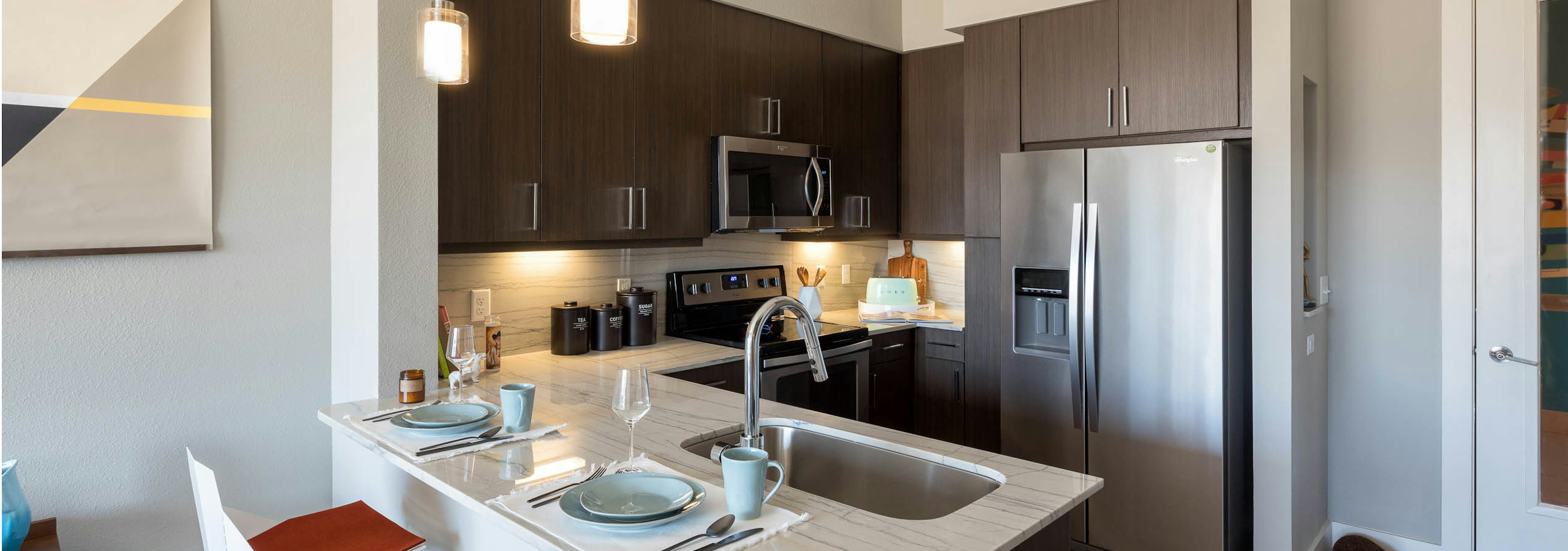 Interior of kitchen at AMLI on Aldrich with dark cabinetry and stainless steel appliances with white quartz countertops