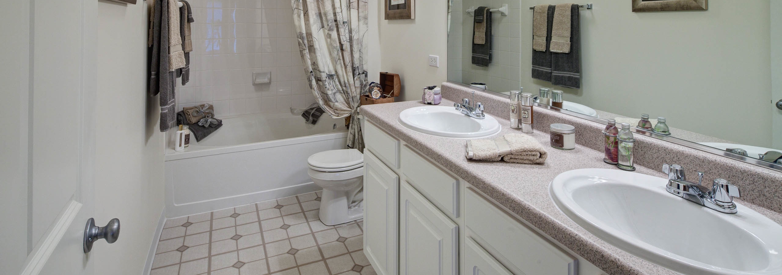 AMLI at Seven Bridges bathroom with a white double vanity next to a toilet with combined tub and shower and patterned floors
