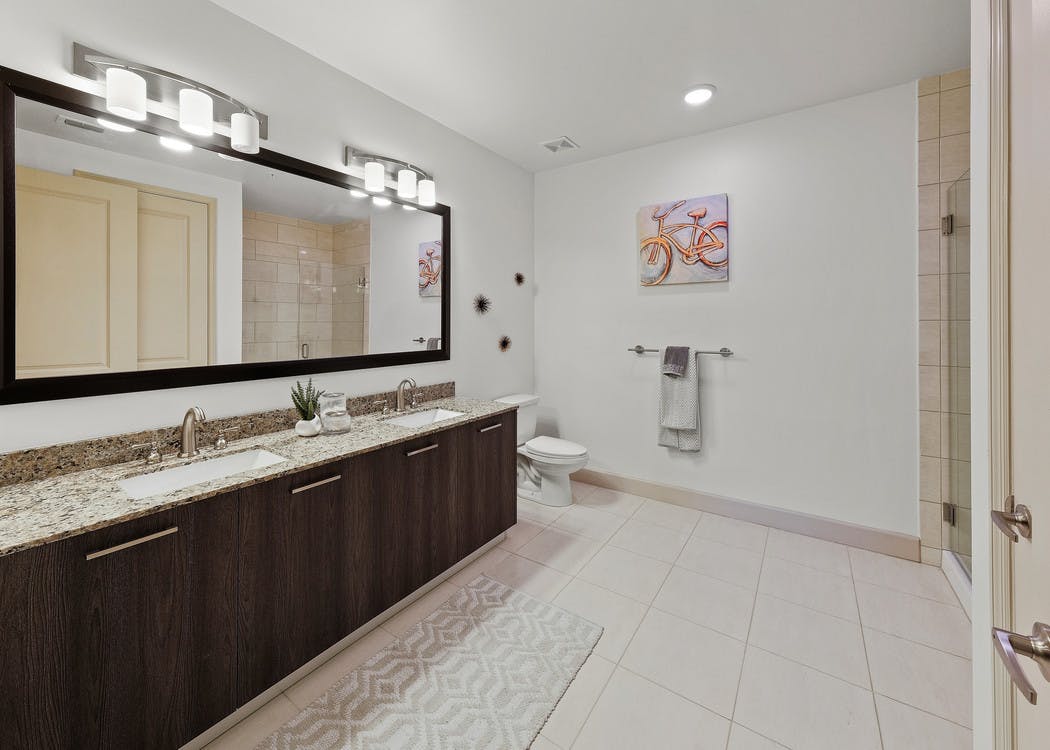 Interior view of AMLI 8800 apartment bathroom with double vanity, mirror, toilet and granite counters