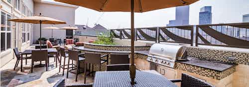 A barbecue area at AMLI Park Avenue apartments with granite and tile counter top space and seating areas and Denver skyline
