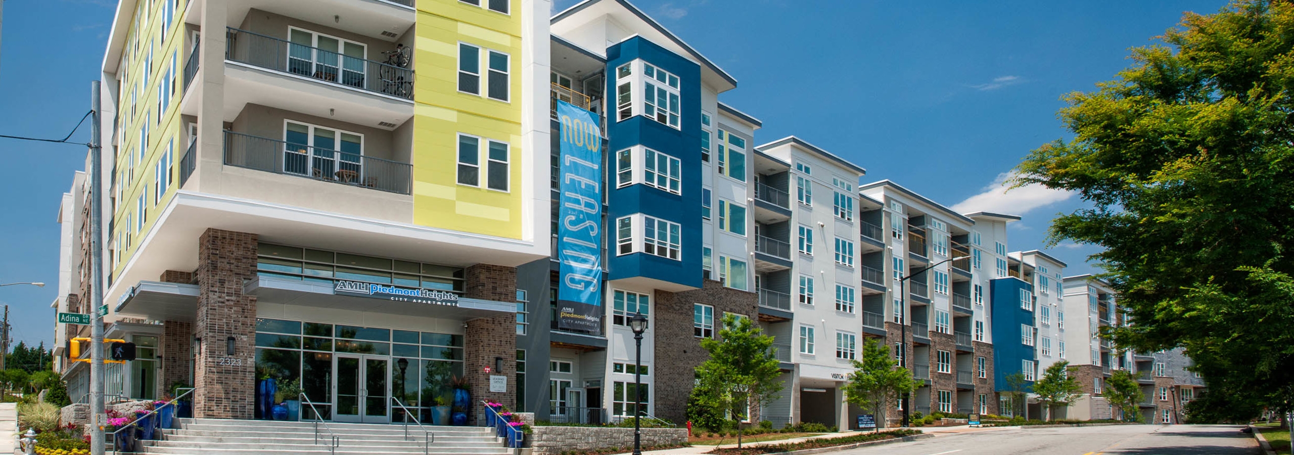 AMLI Piedmont Heights in daylight showing the entrance with steps leading to front door with sign above and lush greenery