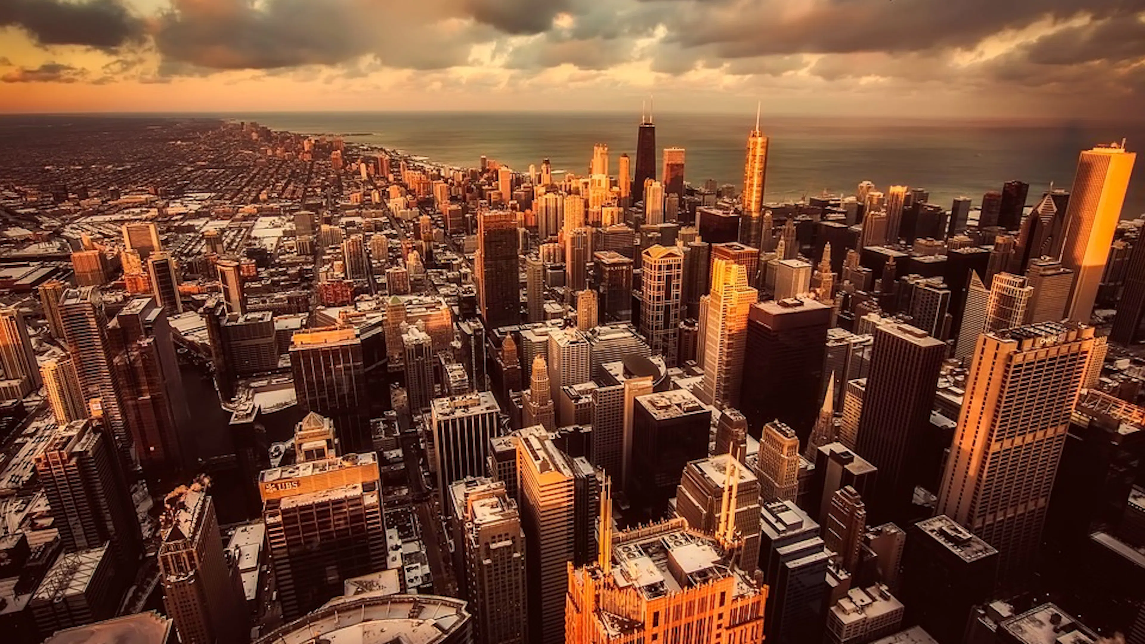 An aerial view of Chicago looking to the north with a bright orange sunset casting light onto the skyscrapers