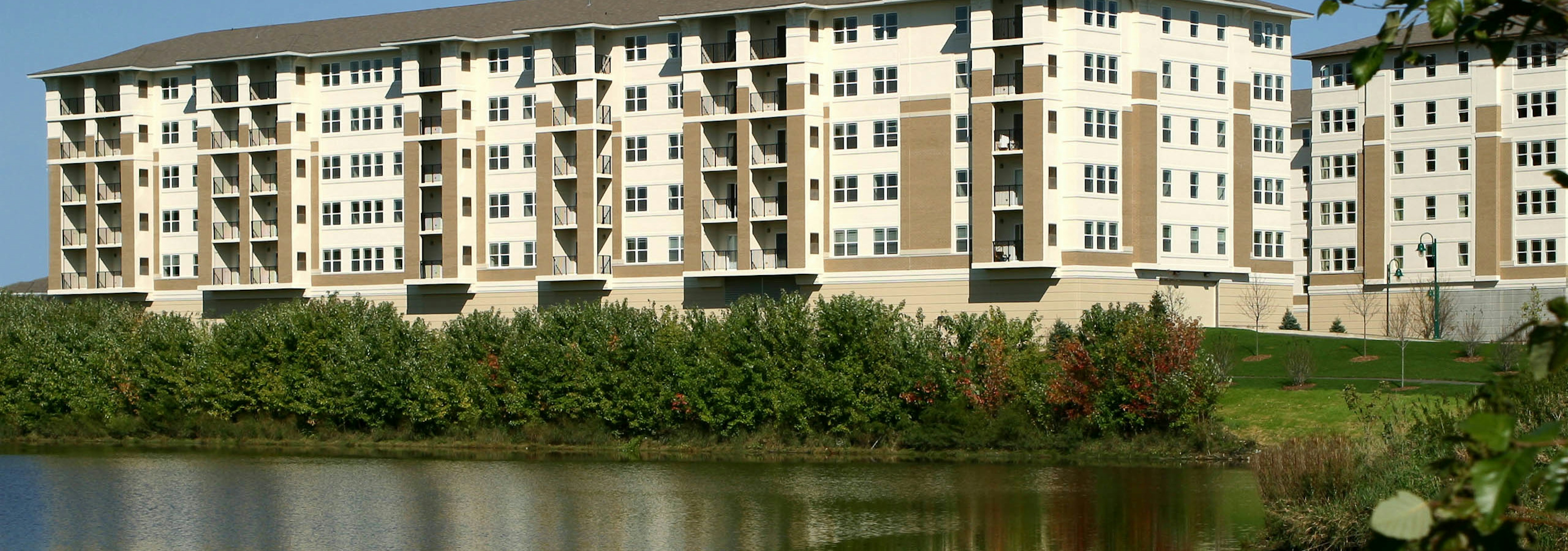 Exterior view of the lakeside AMLI at Seven Bridges apartment community building with a brown and ivory brick facade