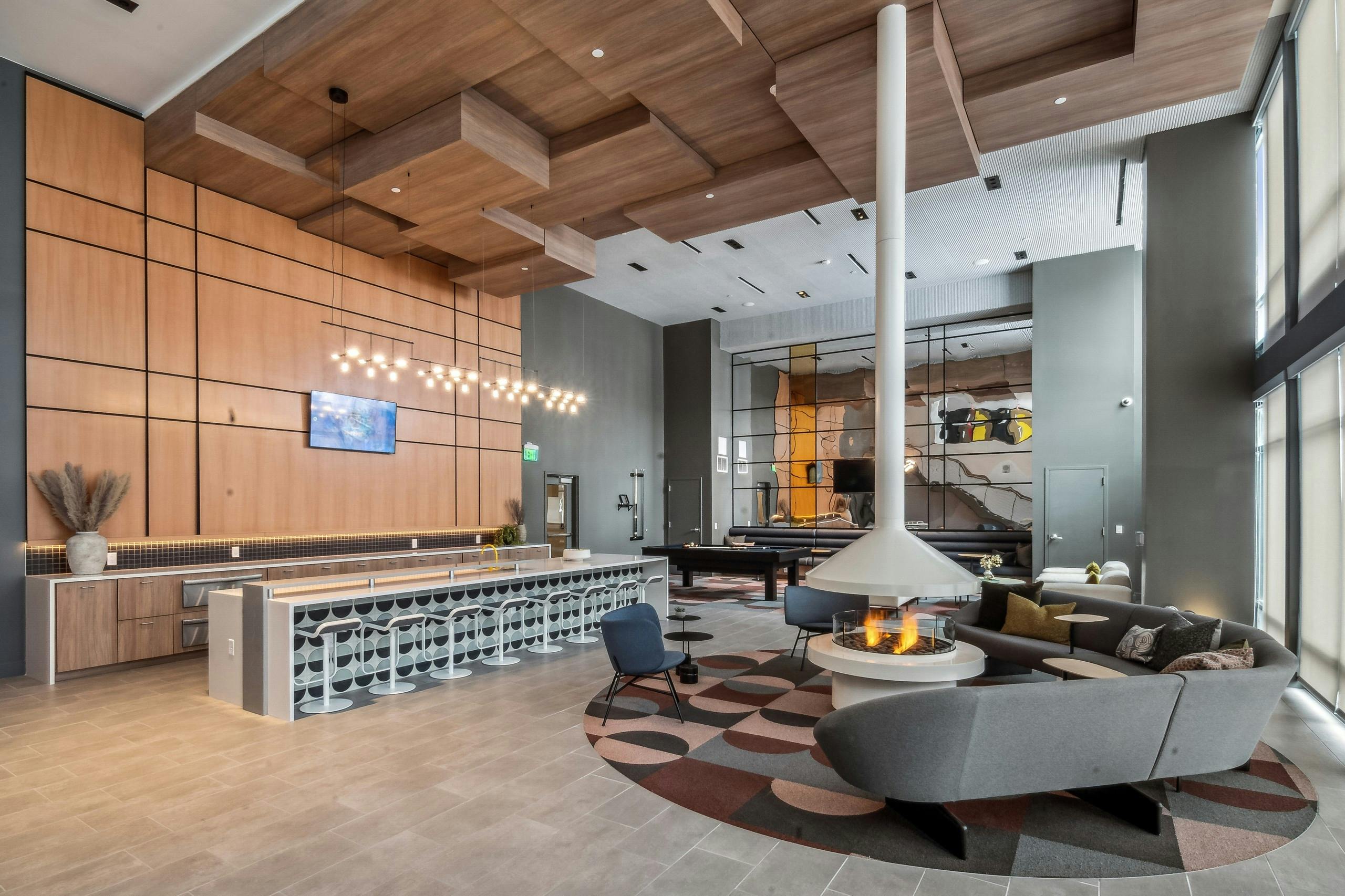 Resident lounge at AMLI Broadway Park with a floor to ceiling white lit fireplace and long pattern bar and many seating areas