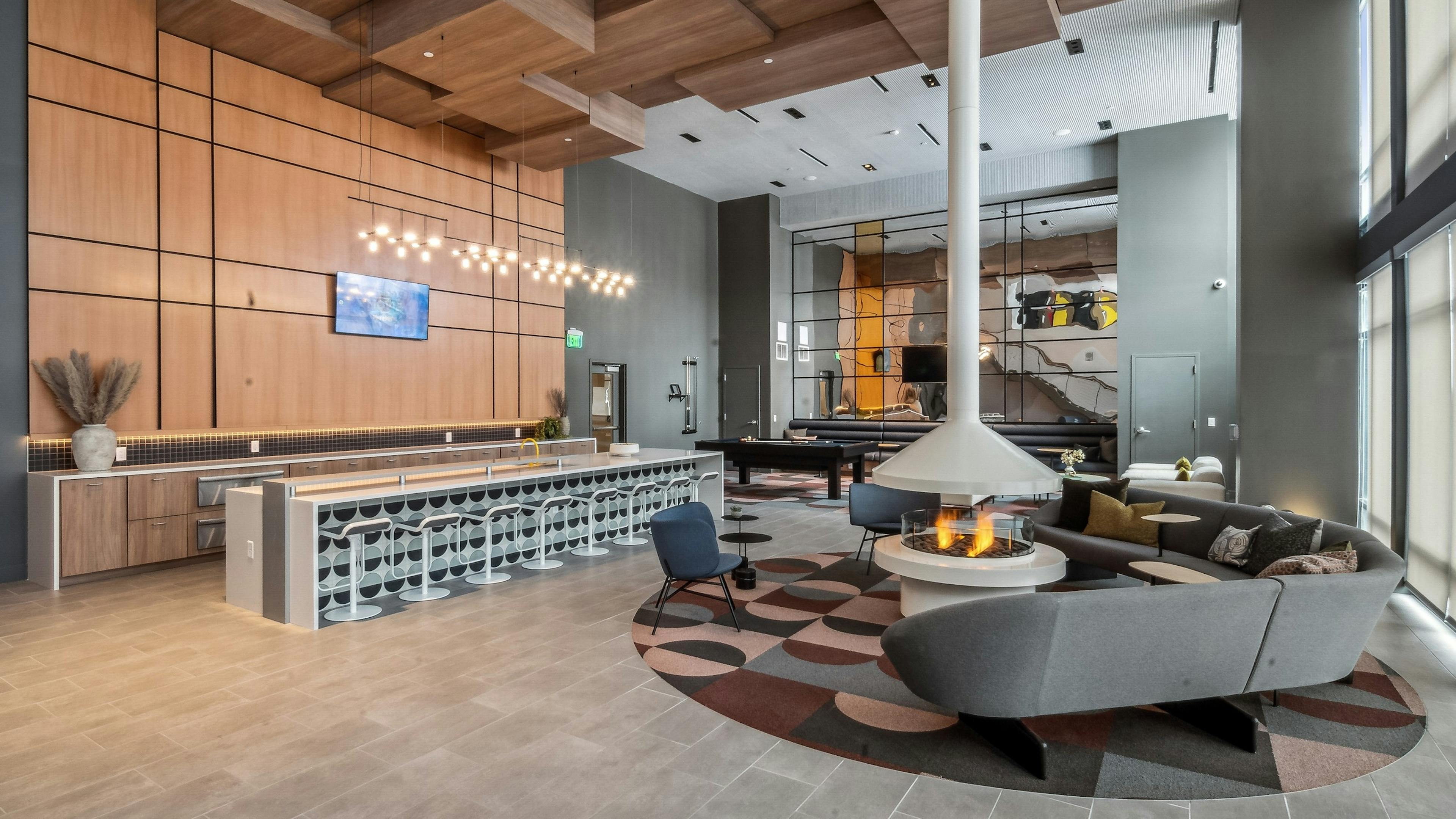 Resident lounge at AMLI Broadway Park with a floor to ceiling white lit fireplace and long pattern bar and many seating areas