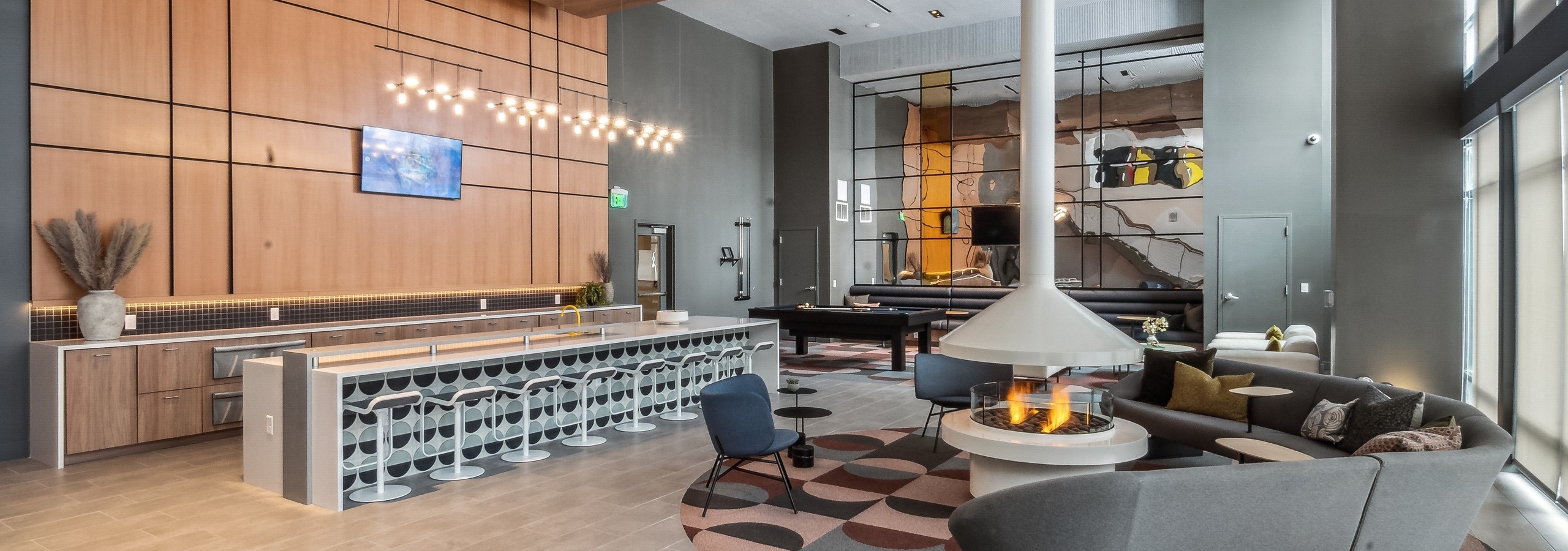 Resident lounge at AMLI Broadway Park with a floor to ceiling white lit fireplace and long pattern bar and many seating areas