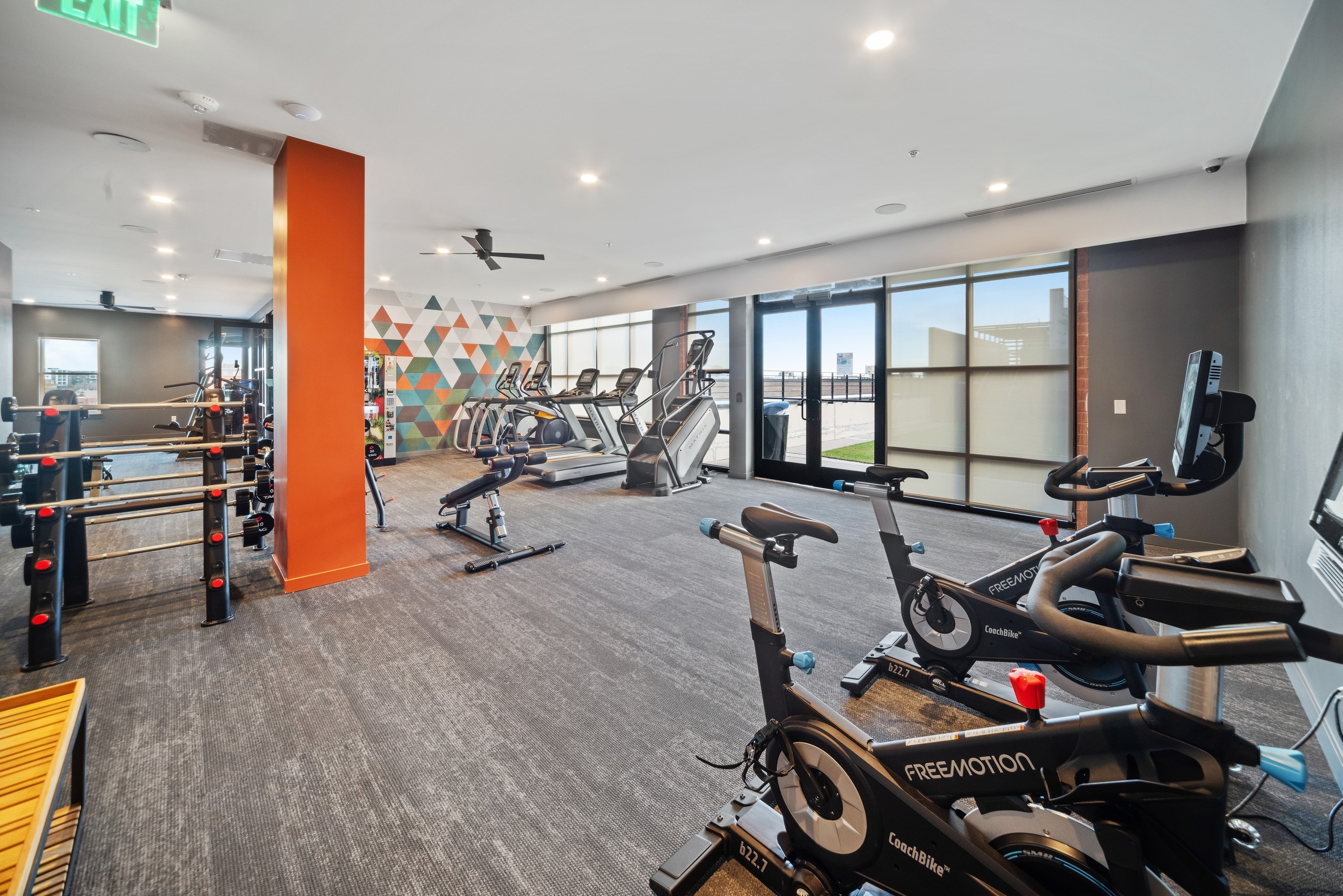 AMLI at Uptown fitness center with grey carpet flooring and floor to ceiling windows featuring a variety of exercise machines