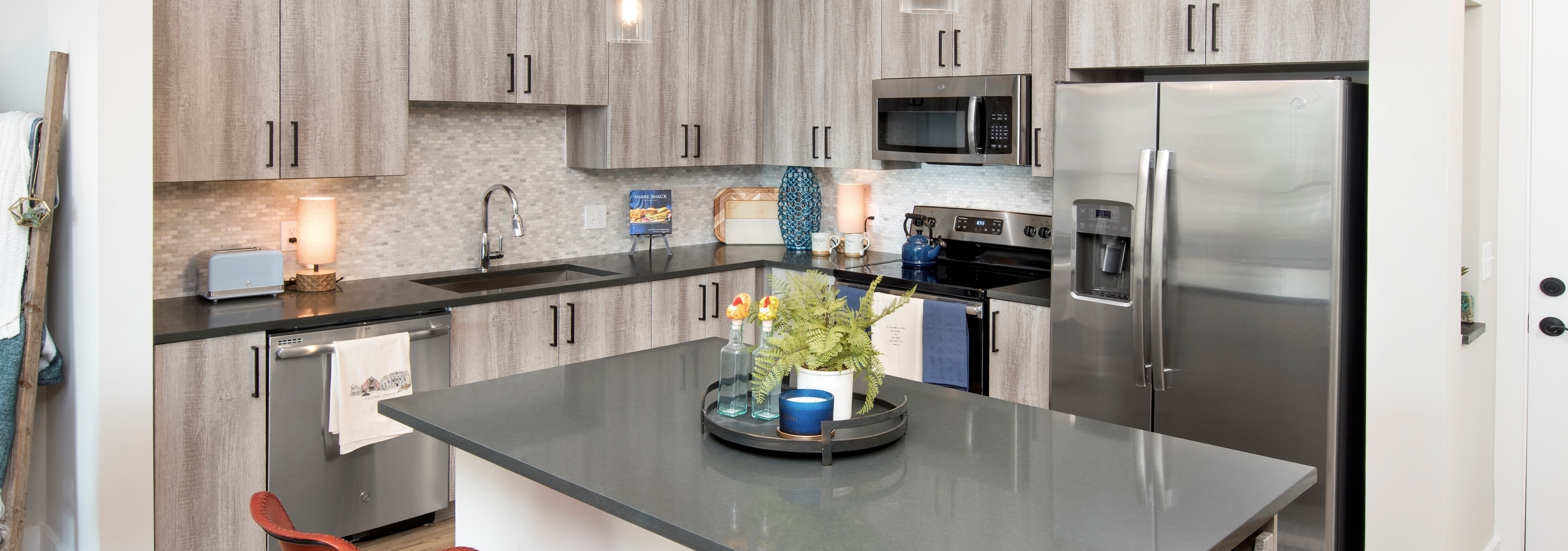 Interior view of AMLI Decatur apartment kitchen with spacious island and stainless steel appliances with a neutral backsplash