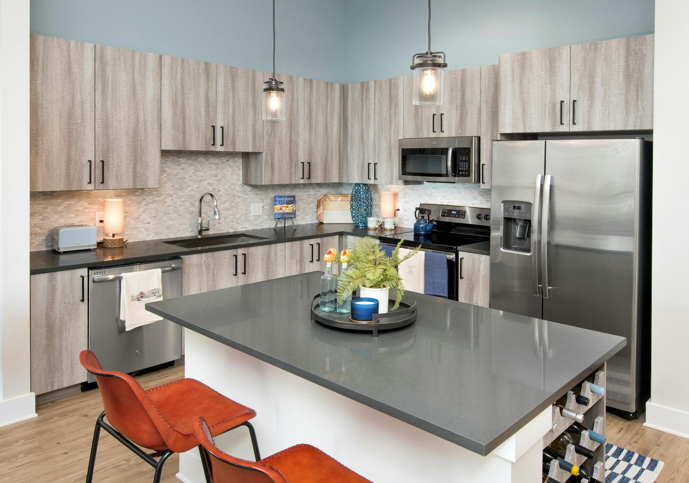 Interior view of AMLI Decatur apartment kitchen with spacious island and stainless steel appliances with a neutral backsplash