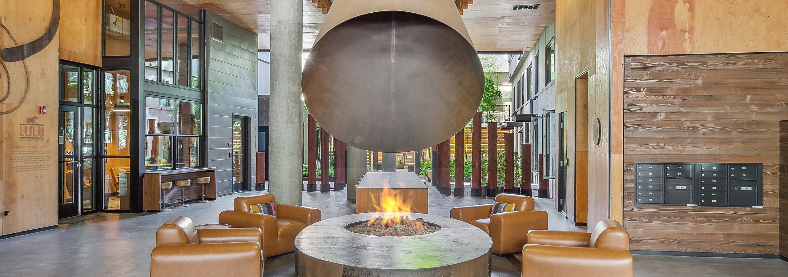 AMLI South Lake Union lobby lounge with lit fire pit with 4 camel leather chairs around it and giant coned flu above
