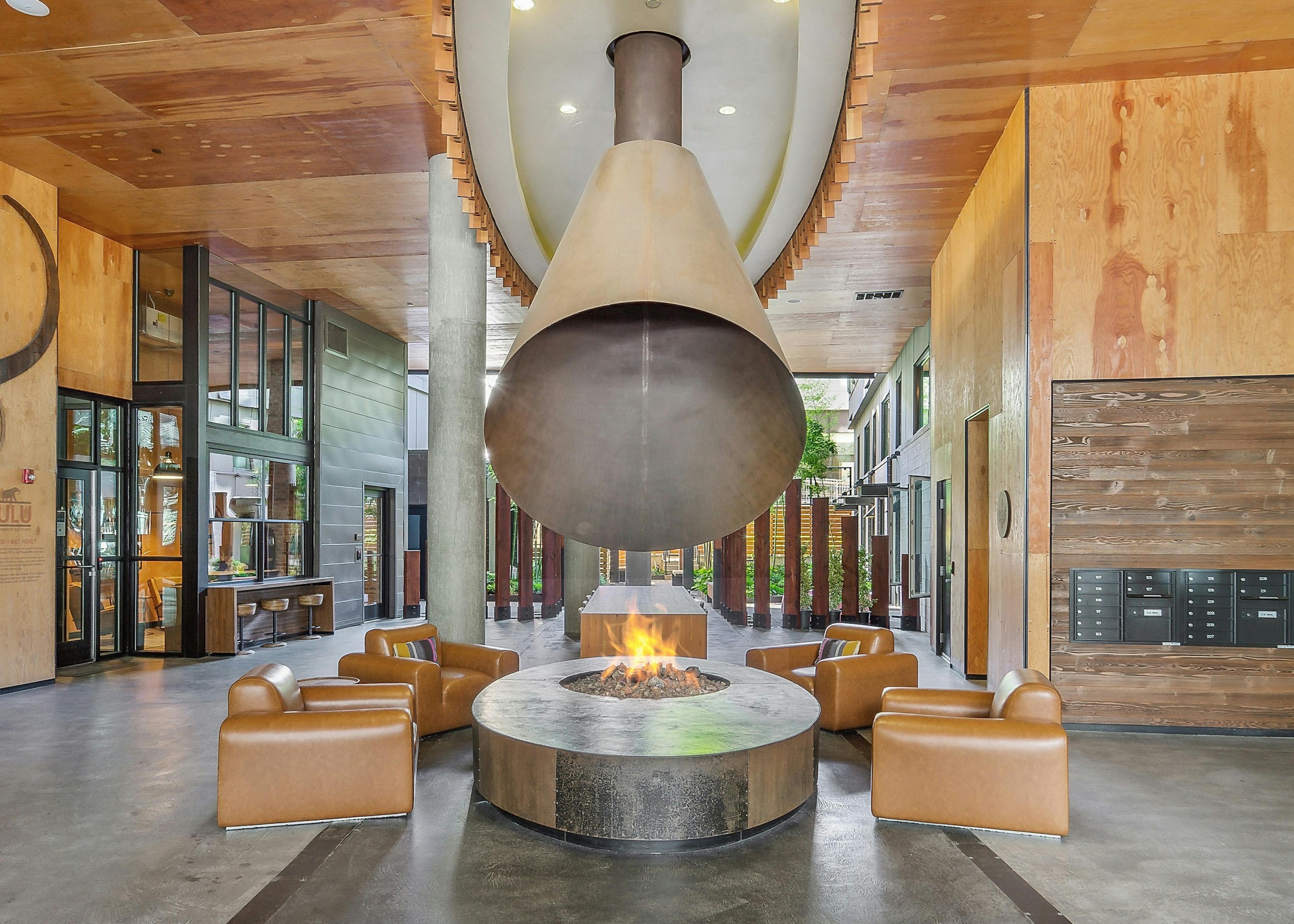 AMLI South Lake Union lobby lounge with lit fire pit with 4 camel leather chairs around it and giant coned flu above