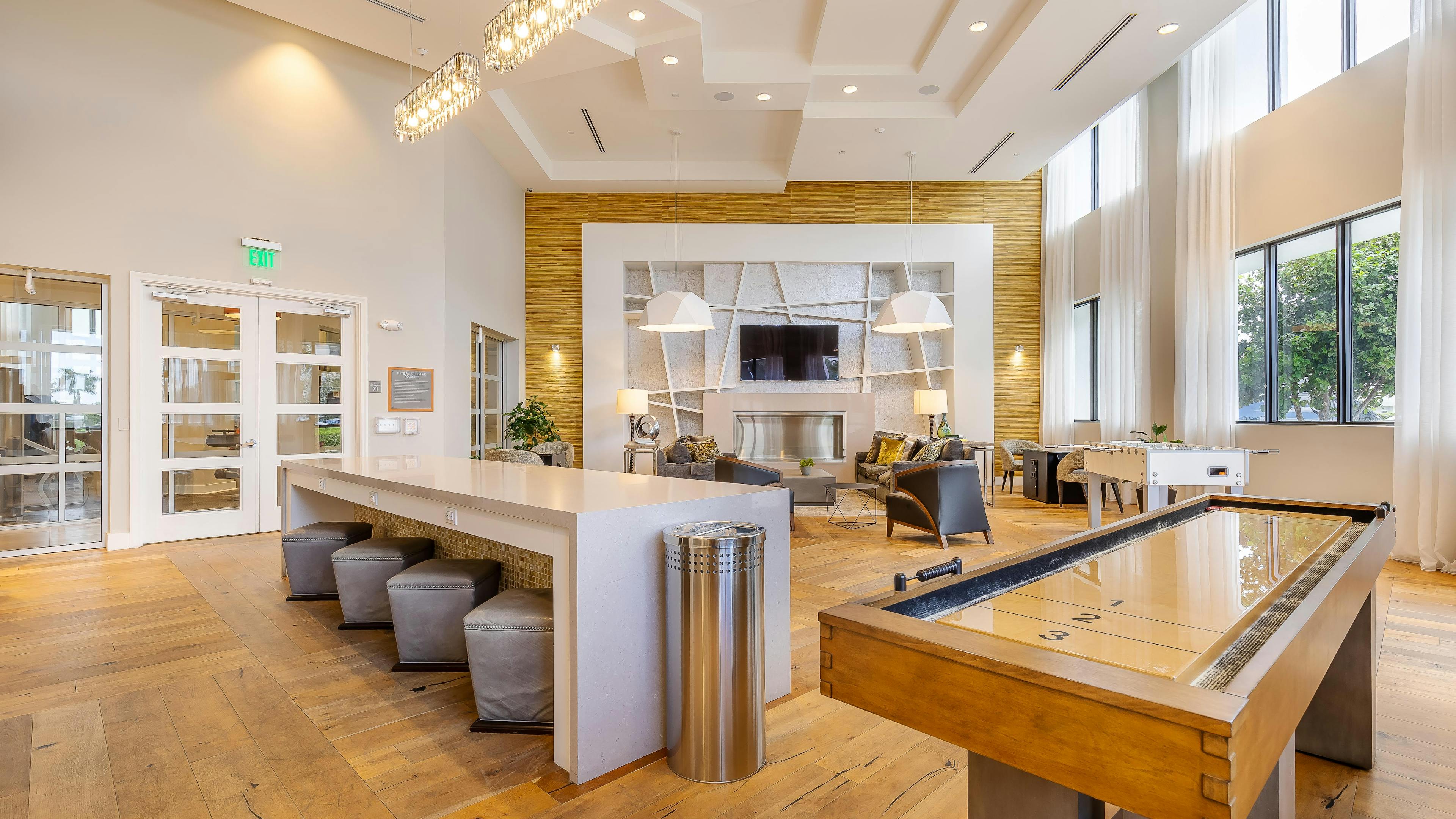 AMLI 8800 apartments resident lounge with shuffleboard and foosball tables and TV on the wall with seating area 