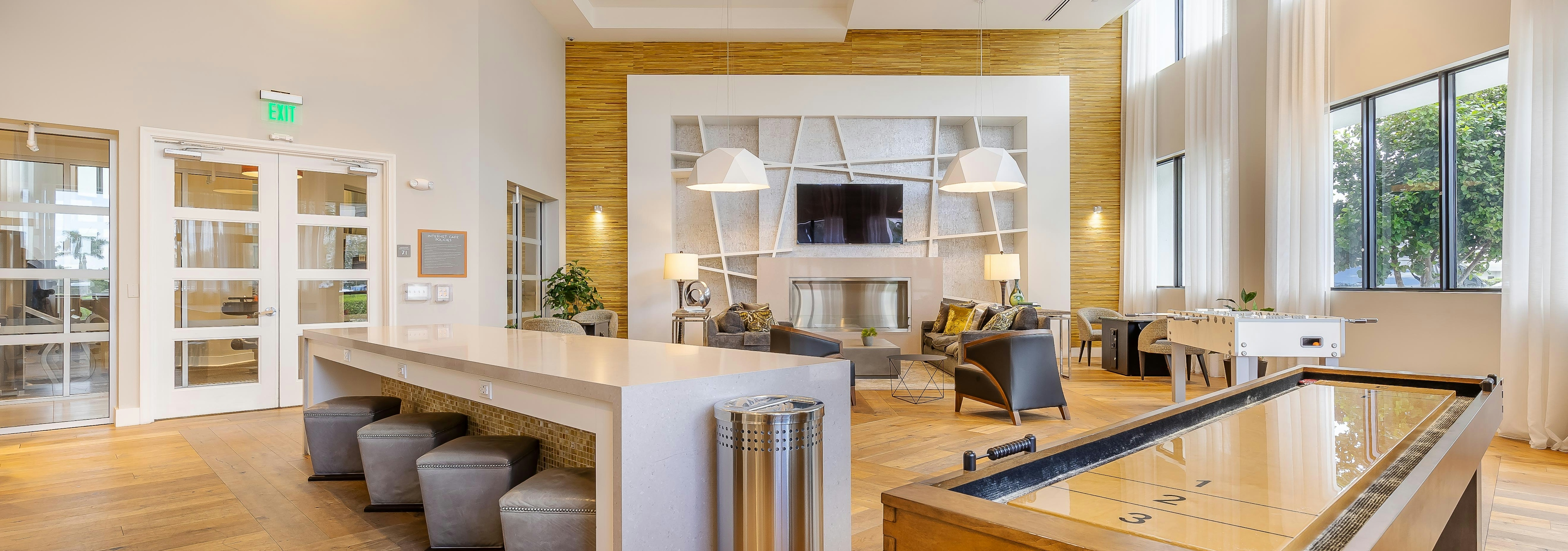 AMLI 8800 apartments resident lounge with shuffleboard and foosball tables and TV on the wall with seating area