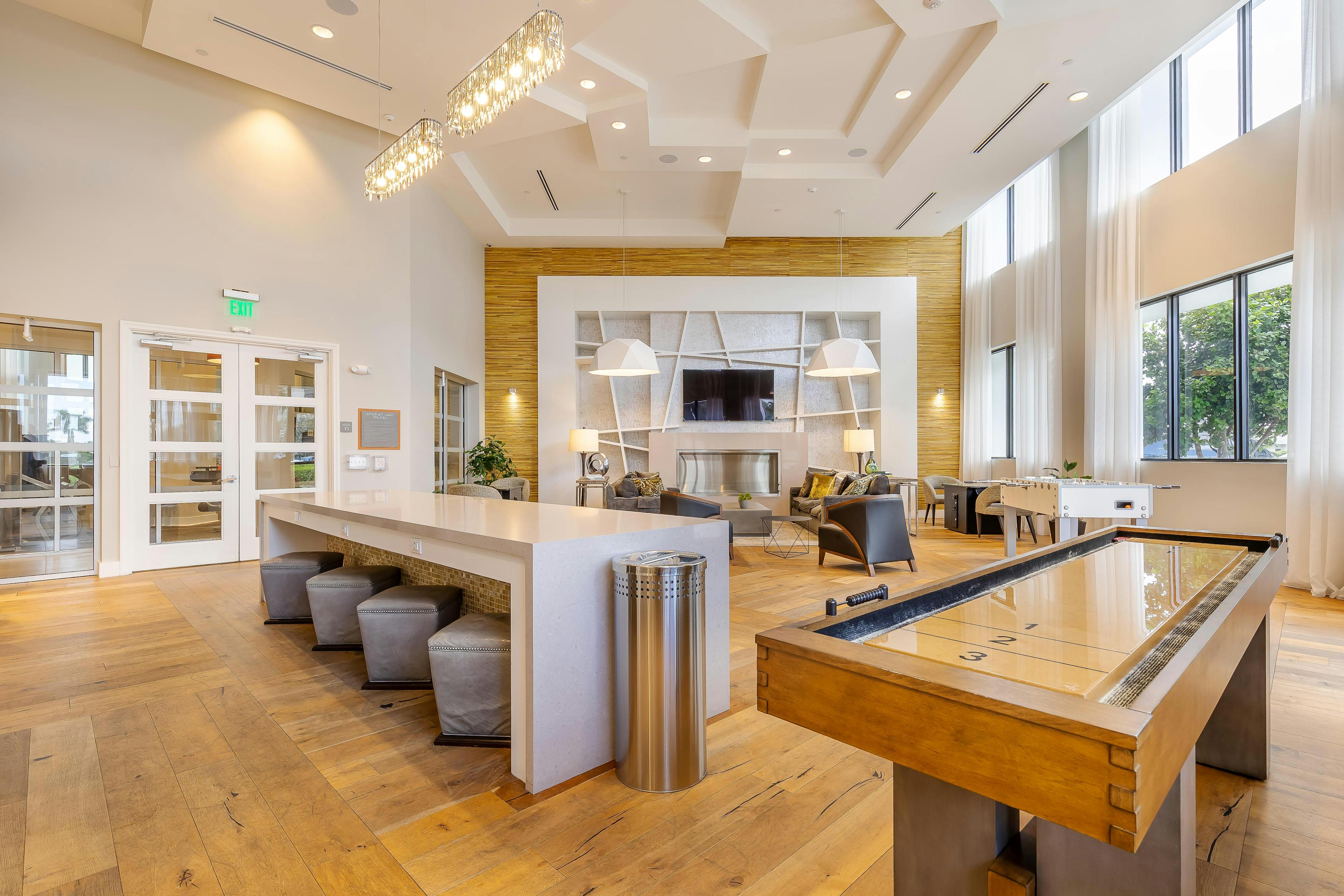 AMLI 8800 apartments resident lounge with shuffleboard and foosball tables and TV on the wall with seating area 