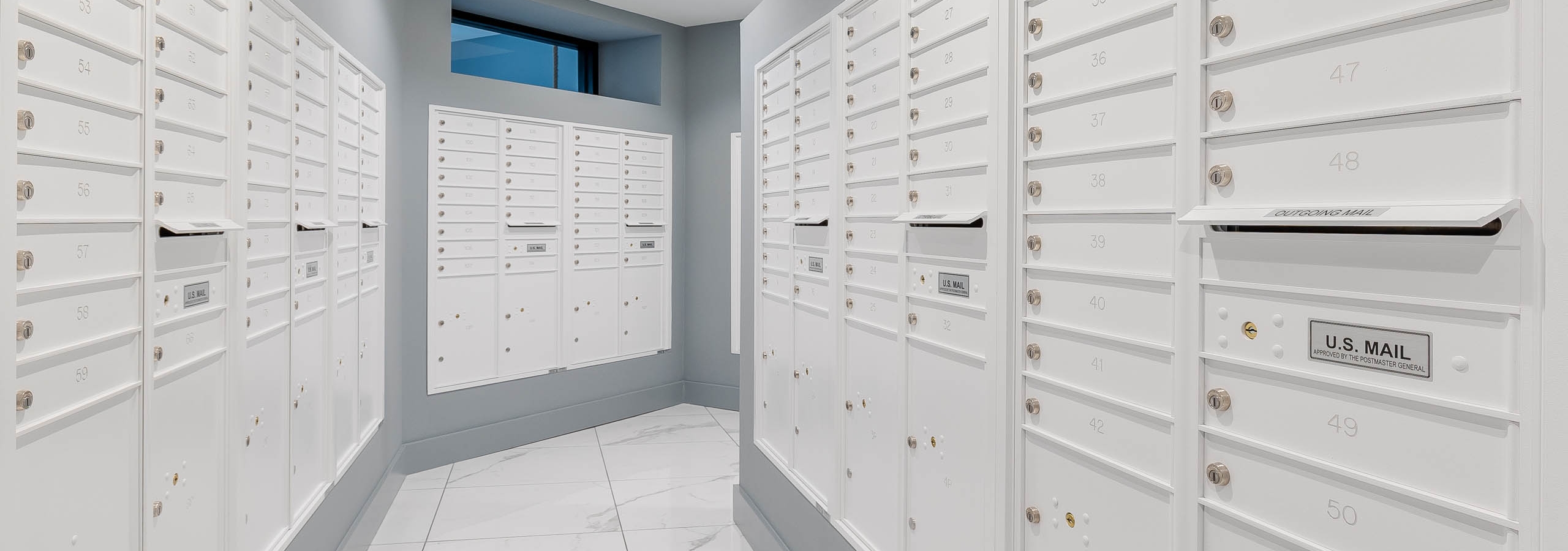 The mailroom at AMLI Park West apartment with marble tile floors and white mailboxes with light gray accent walls