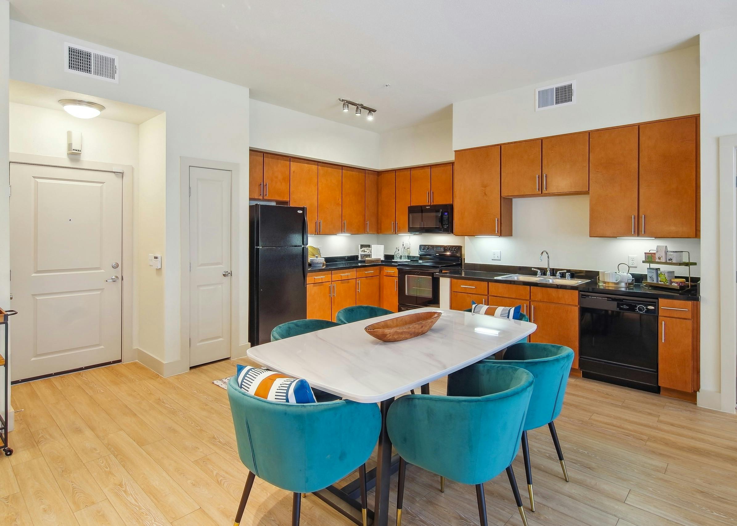 Kitchen and dining area at AMLI Park Avenue apartments with a long black countertop with wood cabinets and dining table