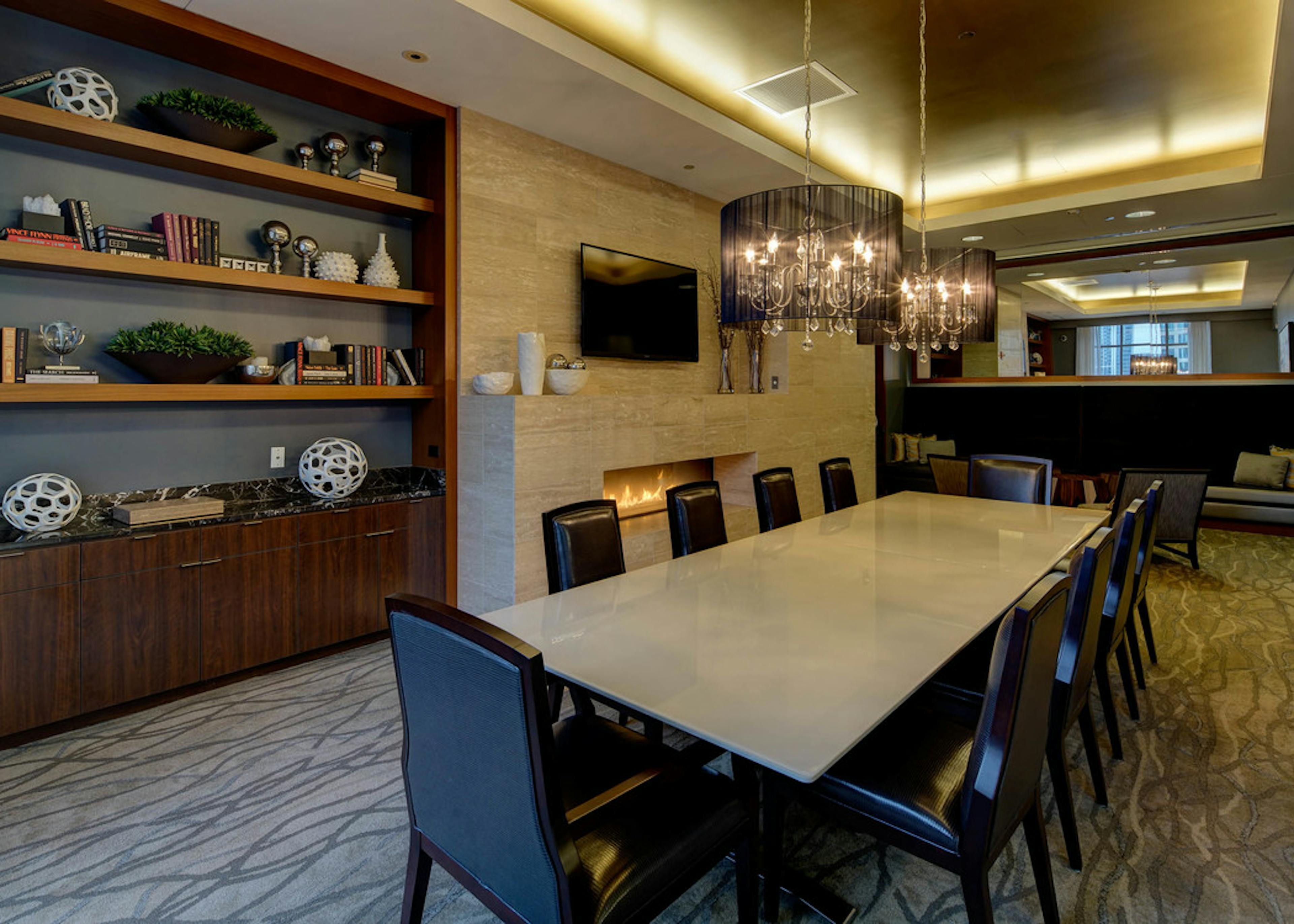 Library at AMLI River North with a long table and black leather chairs and a wooden shelf in the back beside a flat screen TV