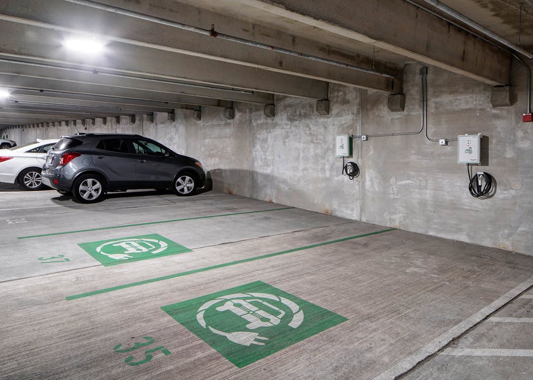 Interior of parking garage at AMLI Deerfield with electric car charging stations and gray and white cars in adjacent spaces
