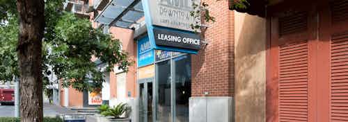Close up daytime view of AMLI Downtown brick apartment building facade with a Leasing Office sign above glass doors