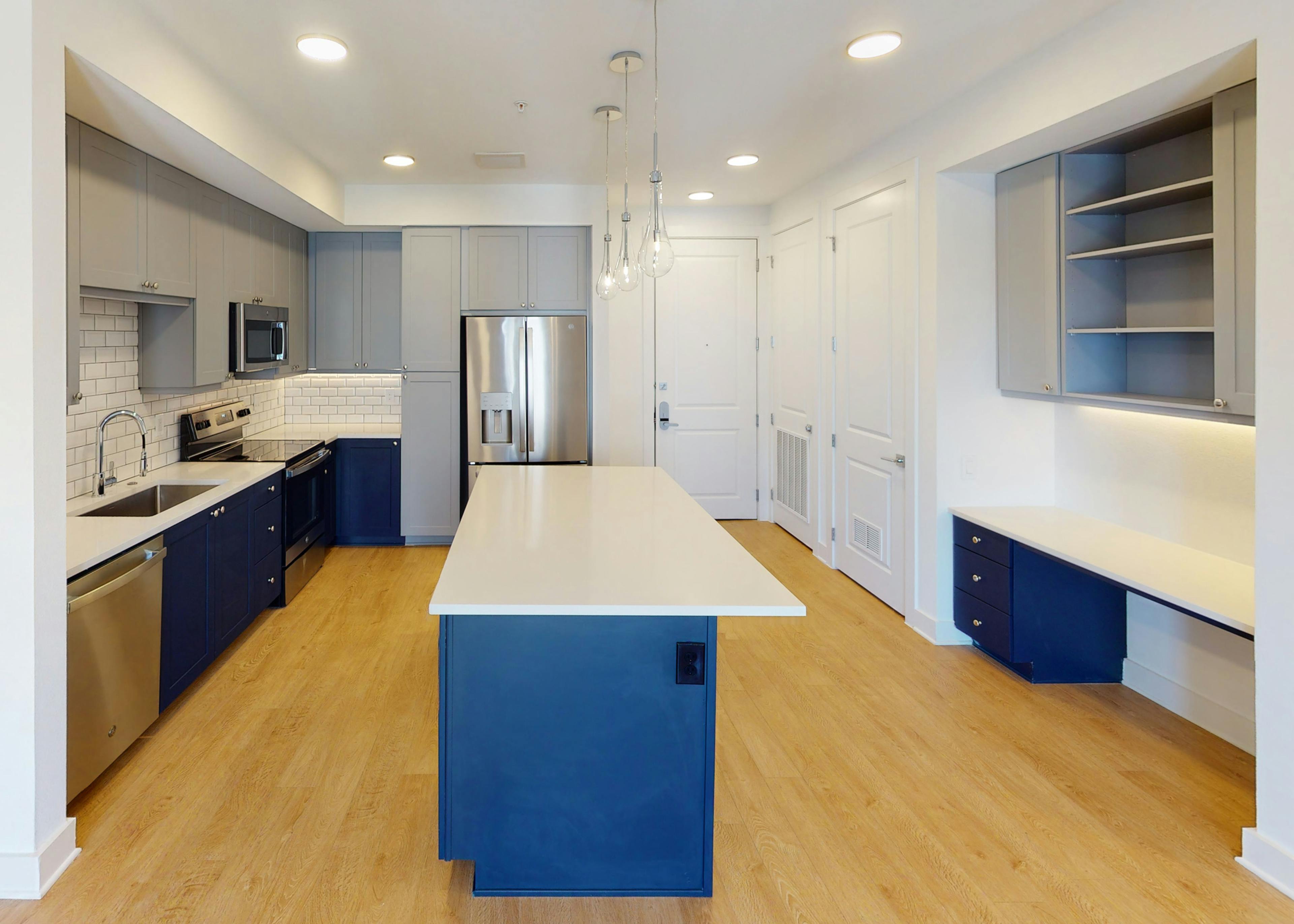 AMLI Branch Park apartment kitchen featuring stainless steel appliances and a blue kitchen island with white countertops