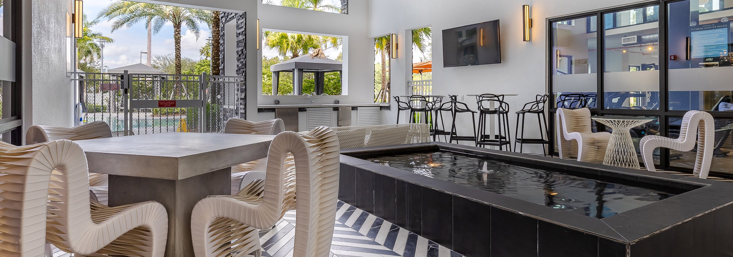 Pool lounge at AMLI Park West apartments with black and white tiled floors and wired outdoor furniture and center fountain