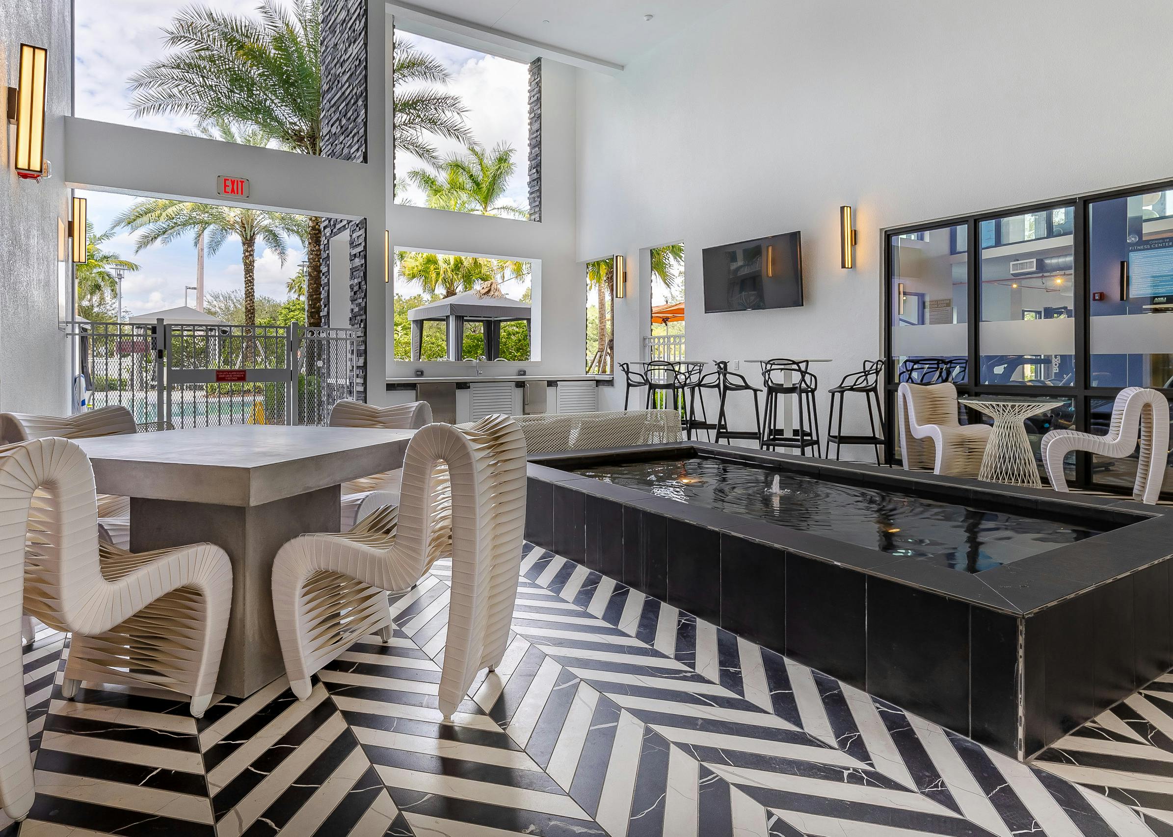Pool lounge at AMLI Park West apartments with black and white tiled floors and wired outdoor furniture and center fountain