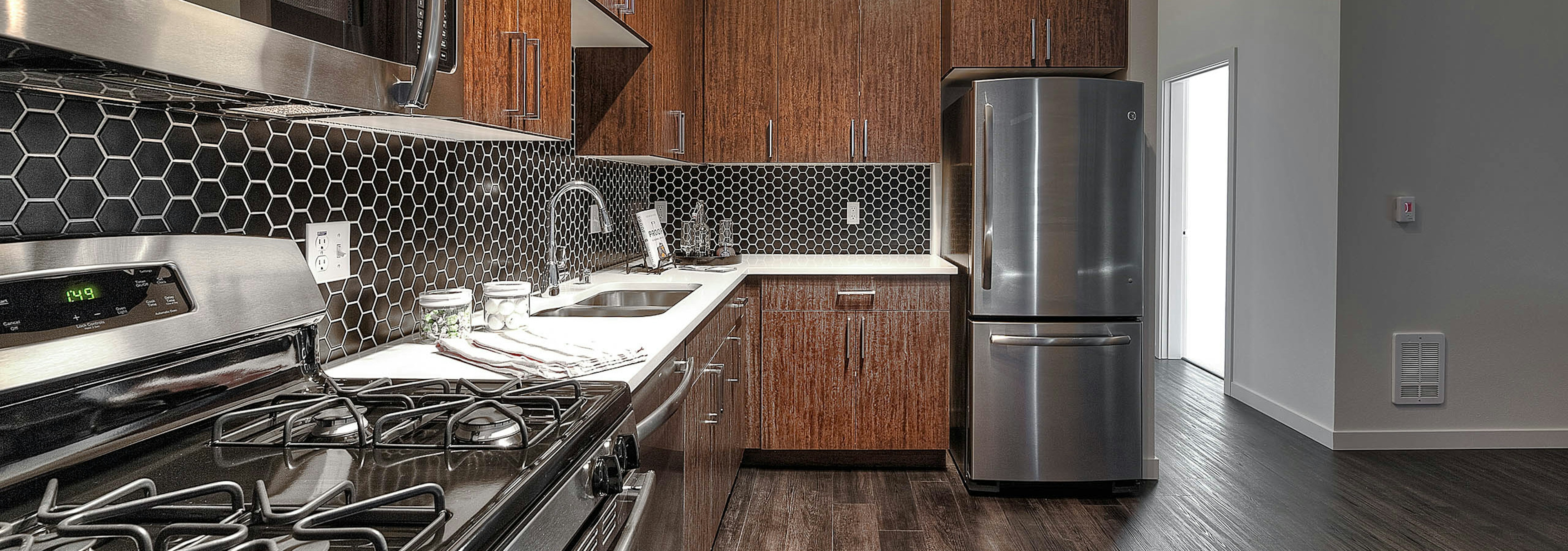 Apartment kitchen at AMLI South Lake Union with dark cabinets and white quartz counters and tile back splash.