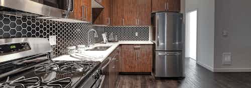Apartment kitchen at AMLI South Lake Union with dark cabinets and white quartz counters and tile back splash.