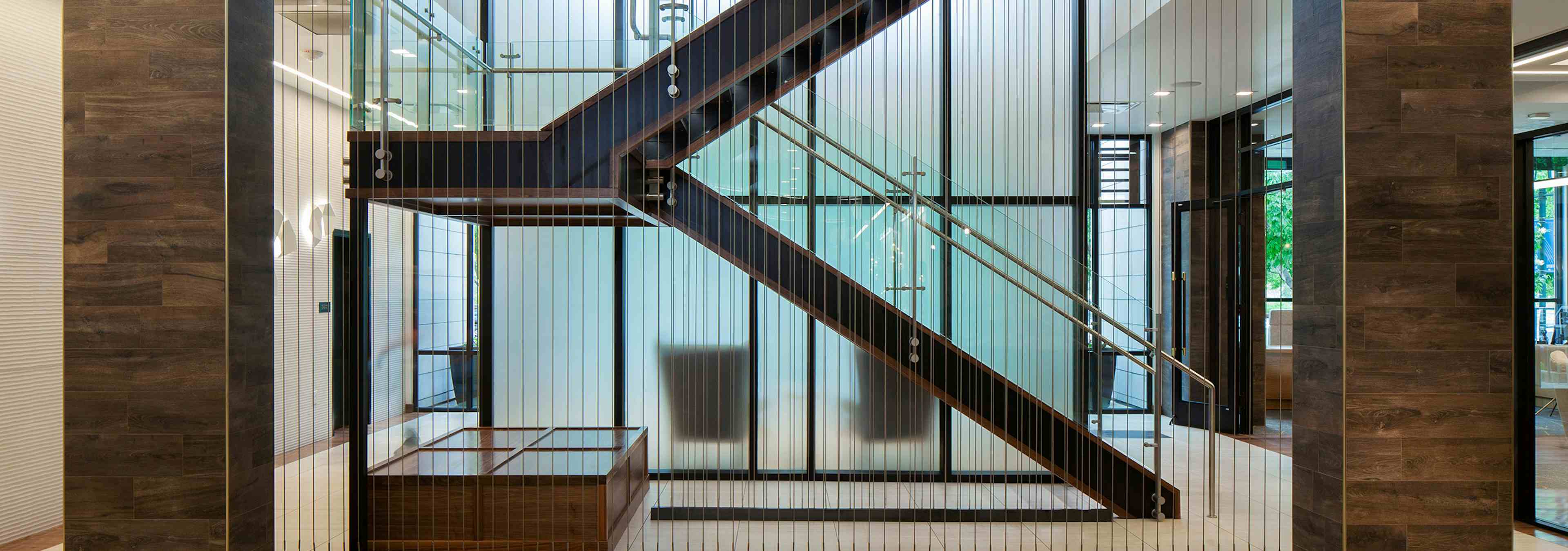 Interior view of the clubhouse at AMLI Riverfront Green apartments with wood panel pillars and staircases with metal railing