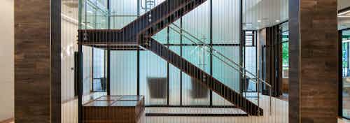 Interior view of the clubhouse at AMLI Riverfront Green apartments with wood panel pillars and staircases with metal railing