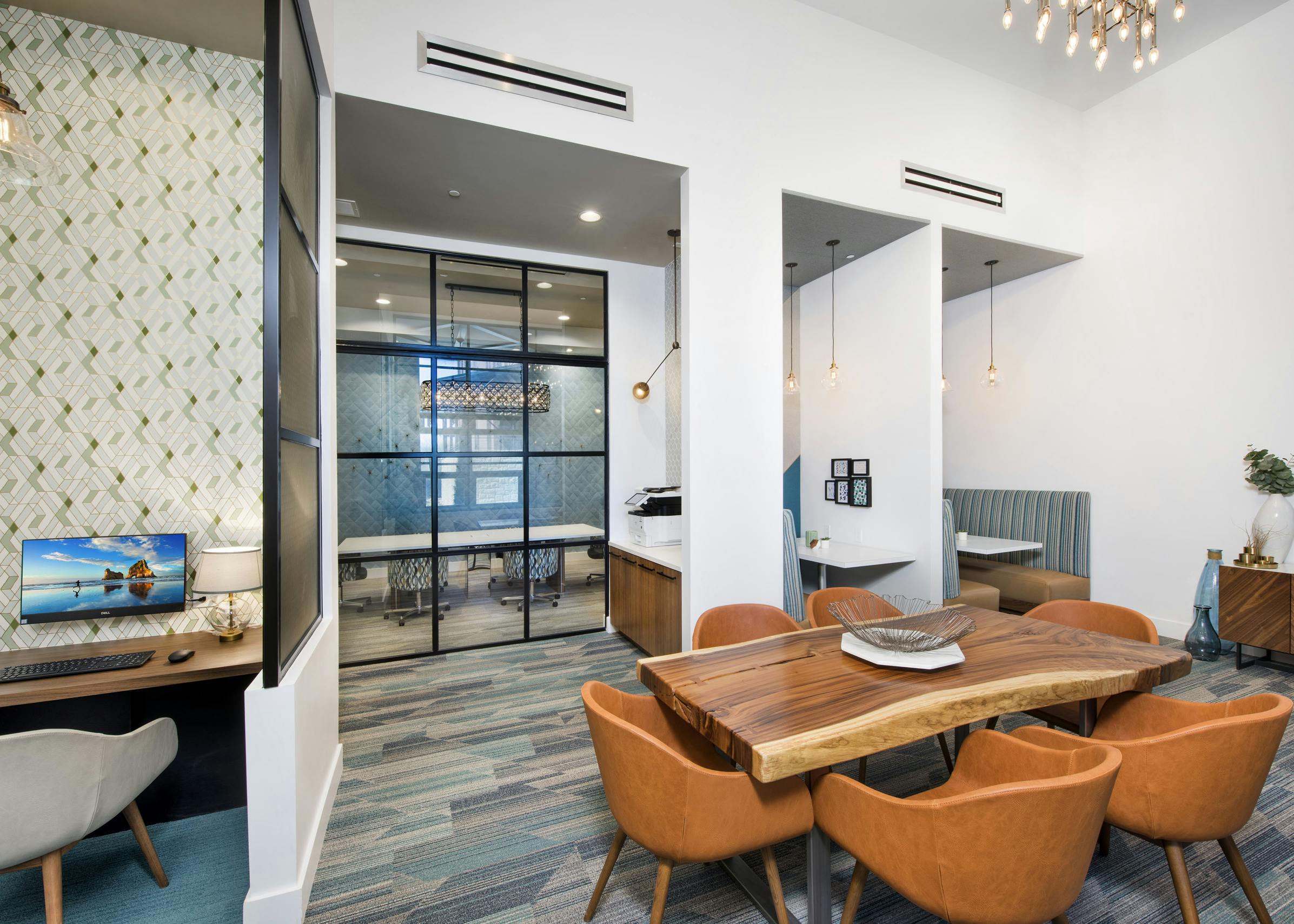 Interior of tech center at AMLI Decatur apartments with computer station and printer and table with six chairs and booths