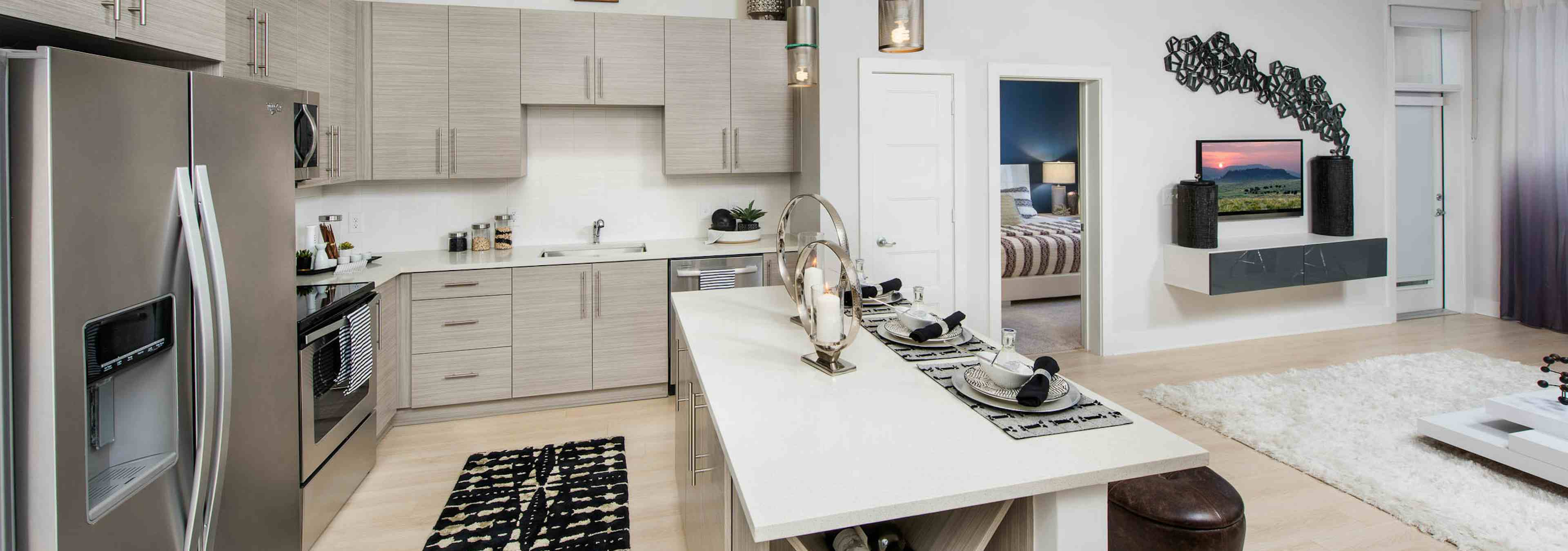 Kitchen at AMLI Buckhead with beige wooden cabinets and a spacious island with light wood floors and a black patterned rug