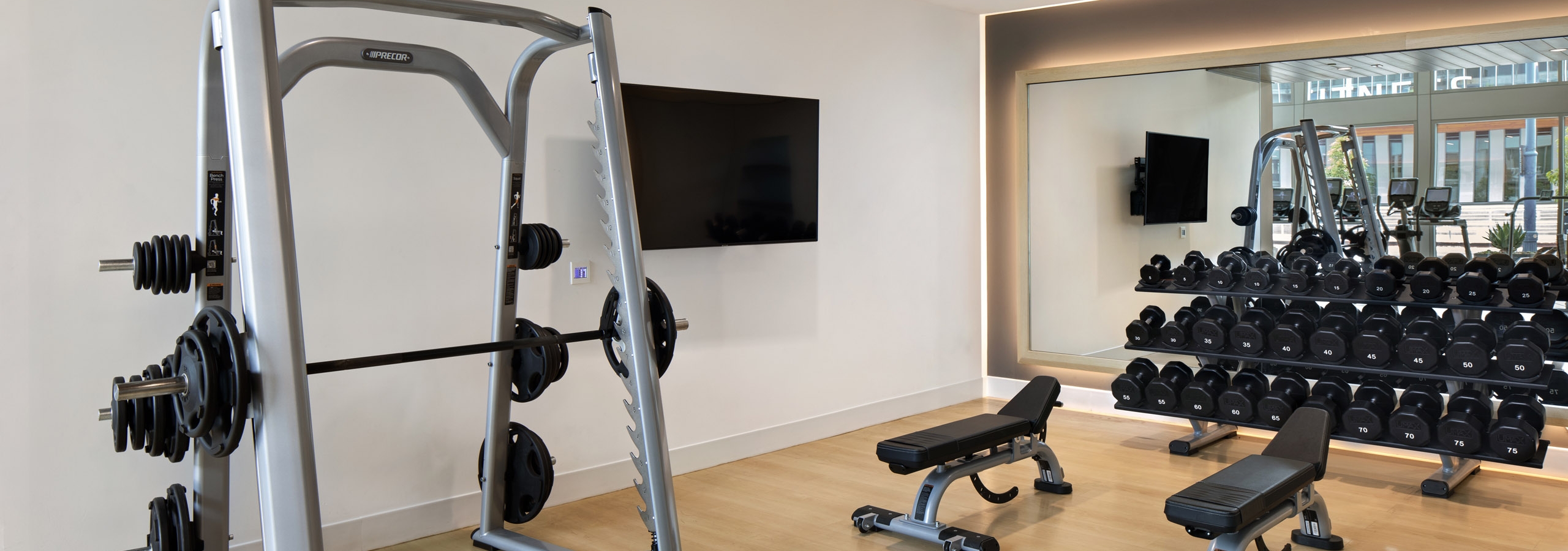 AMLI Park Broadway fitness center with free weights and flat screen TV and weight lifting machine and two benches