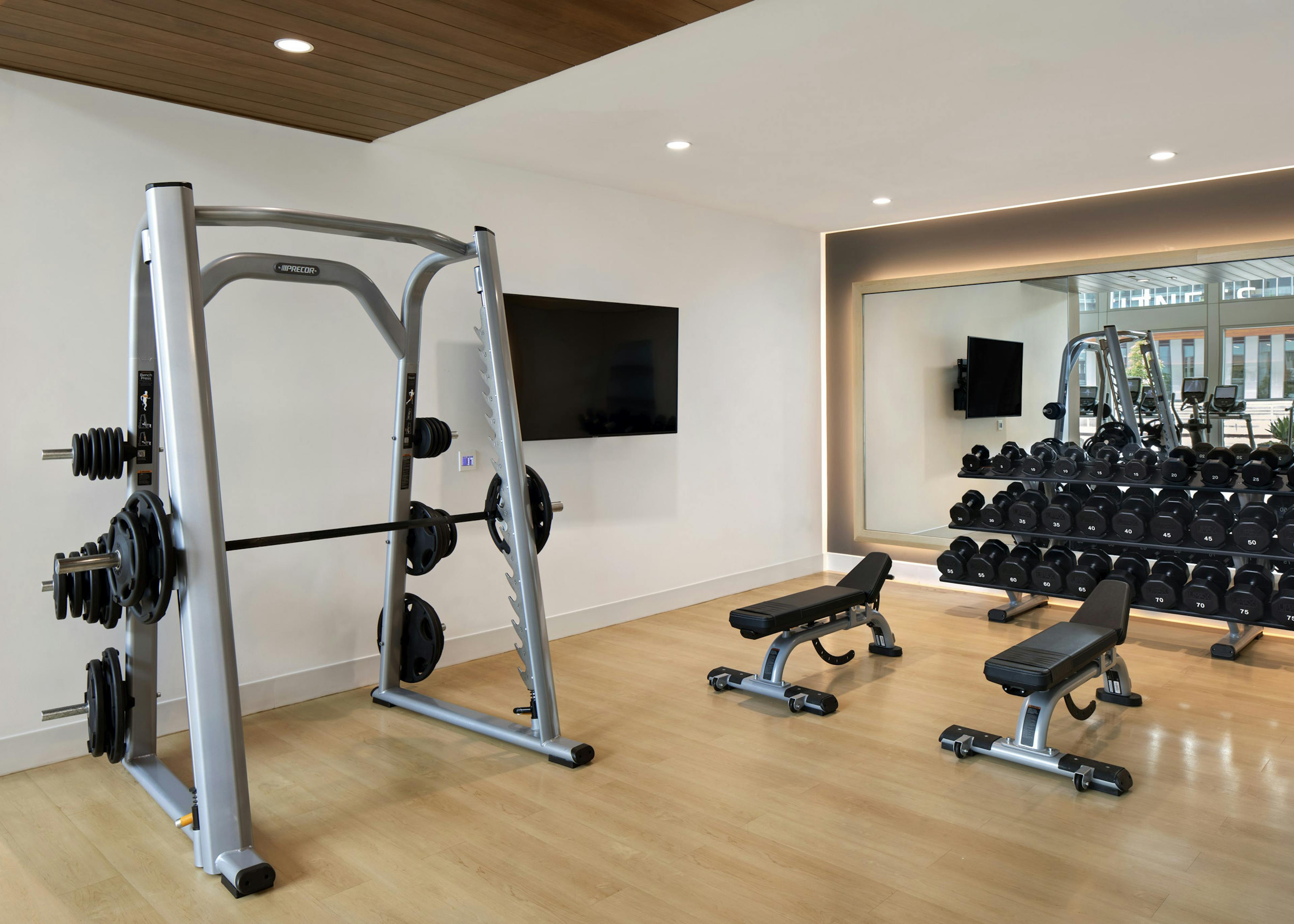 AMLI Park Broadway fitness center with free weights and flat screen TV and weight lifting machine and two benches