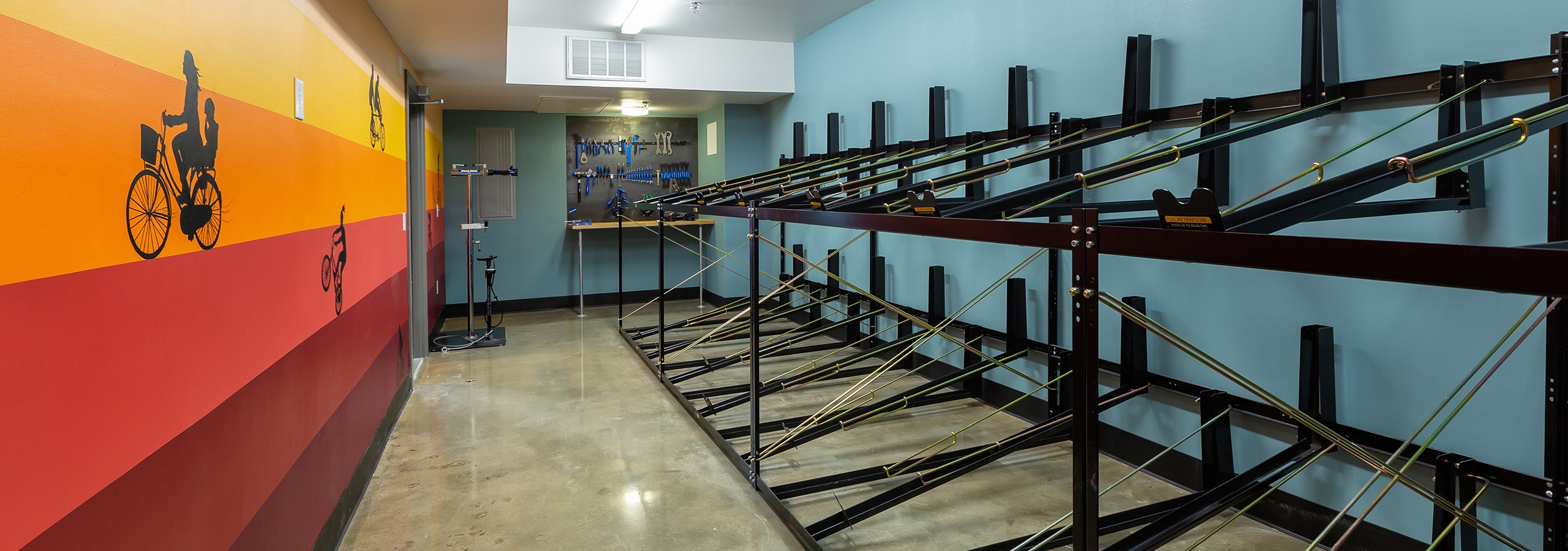 AMLI South Shore bike repair and storage room with bike racks against a light blue wall across from a sunset striped wall