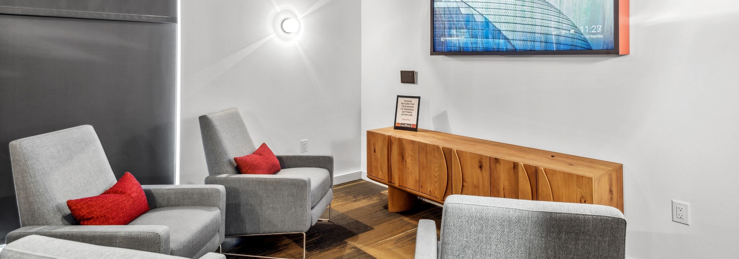 Interior view of a media room at AMLI Wallingford with chairs with red pillows facing large TV over wood chest