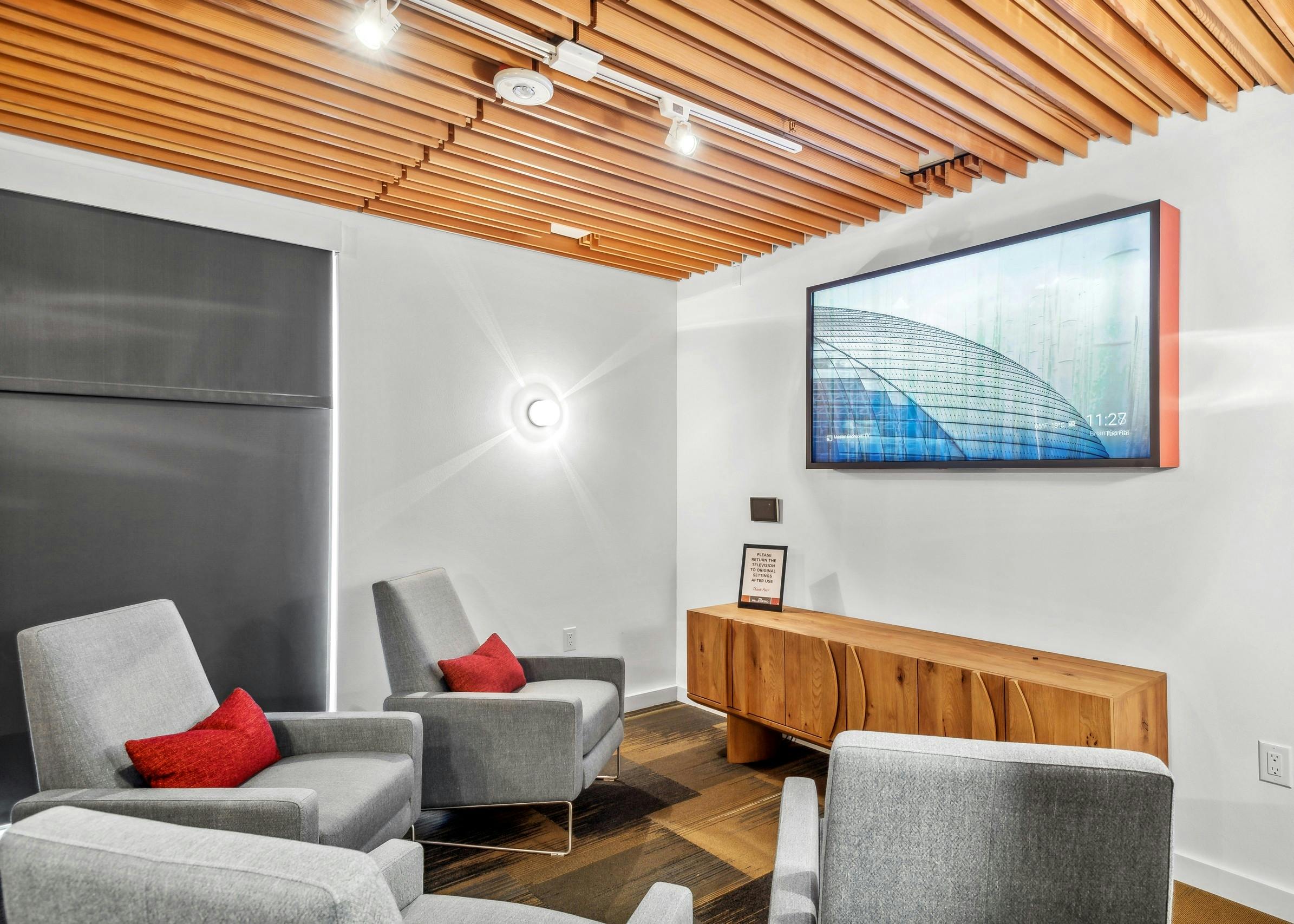 Interior view of a media room at AMLI Wallingford with chairs with red pillows facing large TV over wood chest