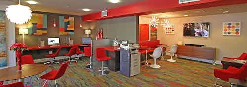 Interior view of AMLI Warner Center business center with computer stations, big screen TV, printer and red lounge seating