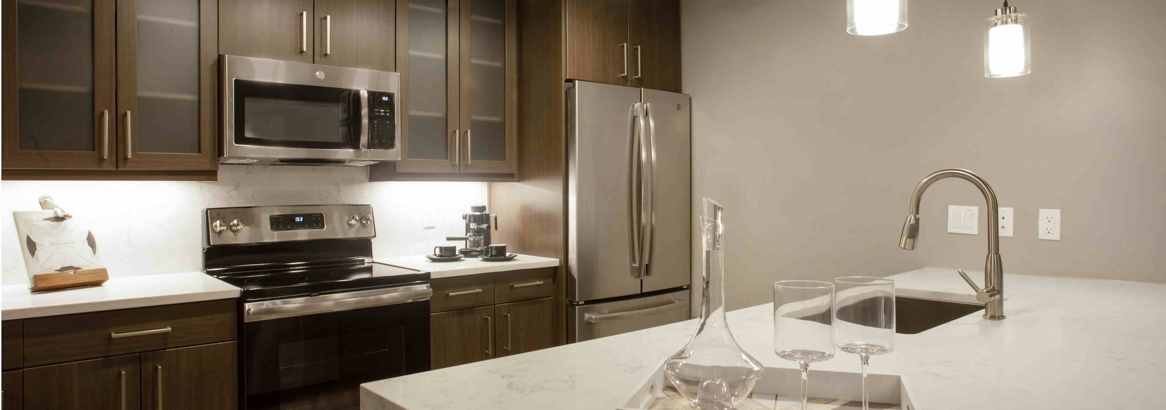 Close up of island in AMLI Downtown kitchen with modern light fixtures above and stainless steel appliances in background