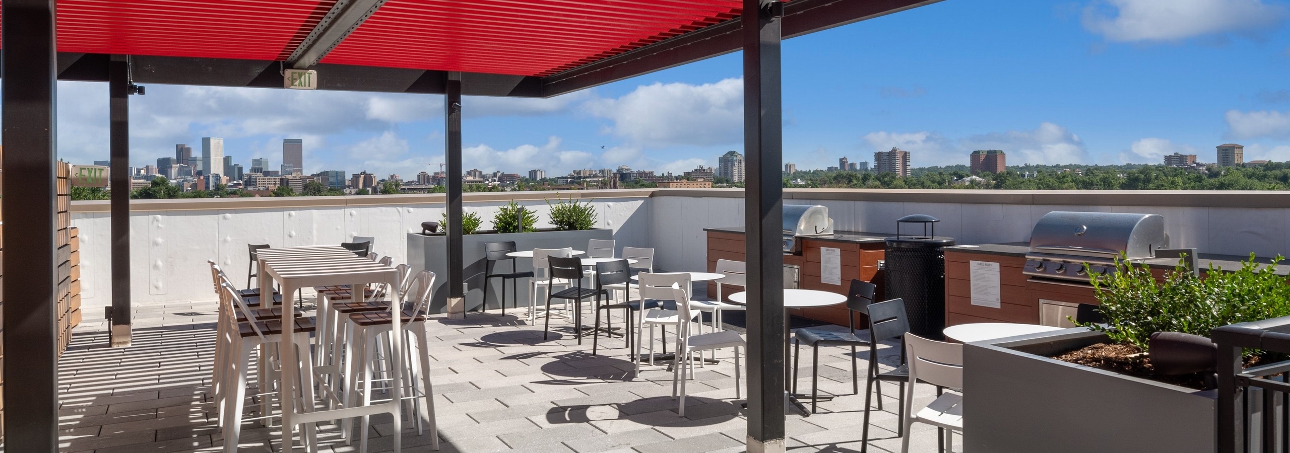 Rooftop at AMLI Broadway Park with large red and black arbor and grills surrounded by tables and chairs with skyline view