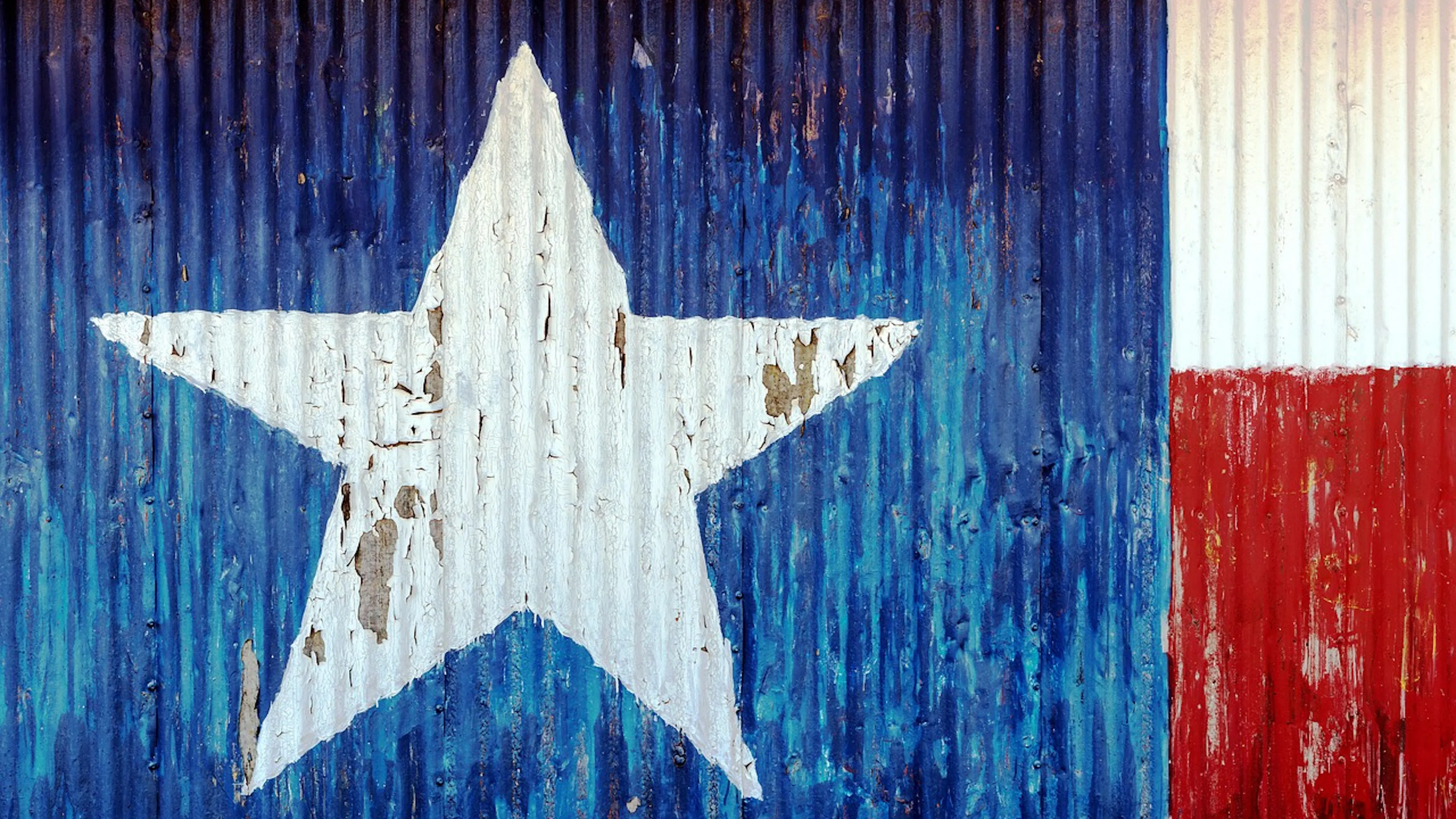 A large piece of sheet metal painted in the colors and shapes of the Texas flag that has a blue square with a white star