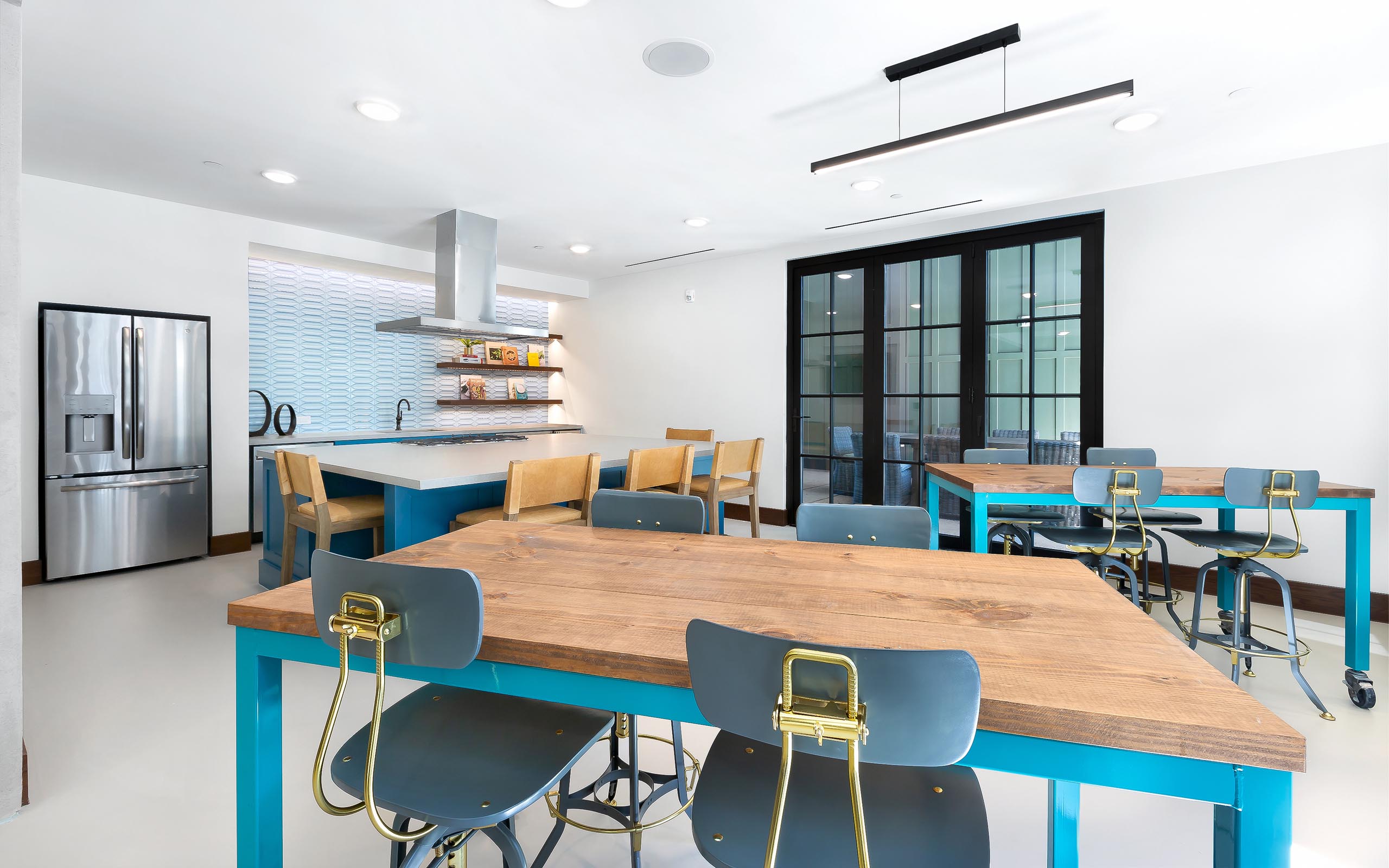 Interior view of resident kitchen with stainless steel appliances and three tables with chairs at AMLI Lakeline apartments