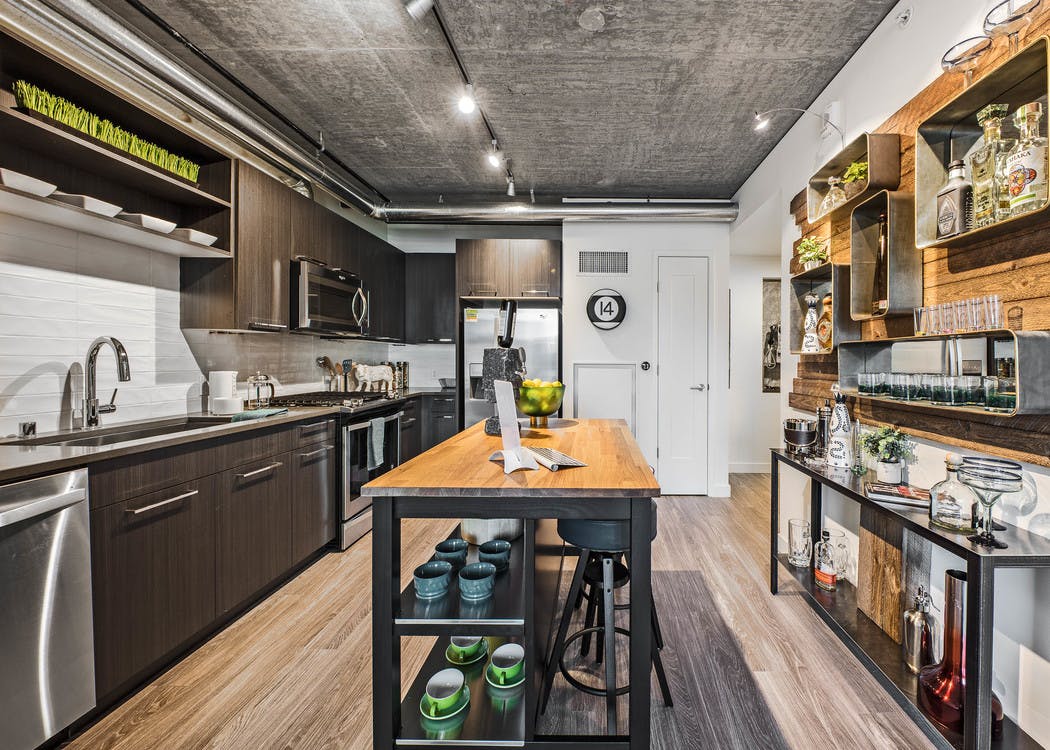 Interior view of apartment of AMLI Arc of kitchen with dark cabinets stainless steel appliances and entry way