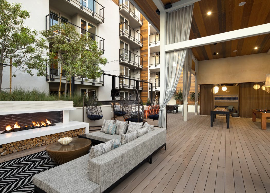 Exterior daytime view of lanai at AMLI Marina Del Rey apartments with fireplace, comfy sectional and teardrop hanging chairs