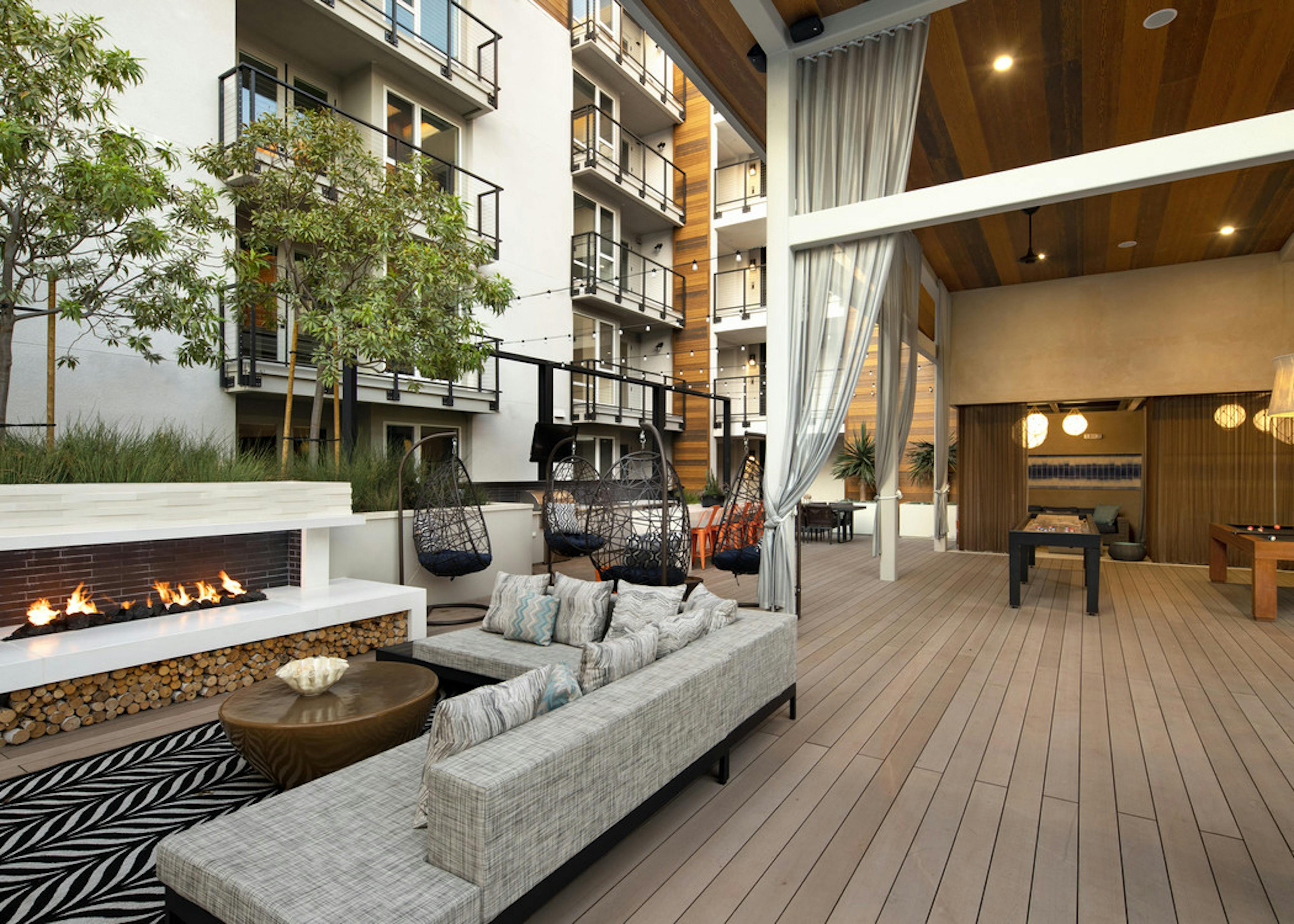 Exterior daytime view of lanai at AMLI Marina Del Rey apartments with fireplace, comfy sectional and teardrop hanging chairs